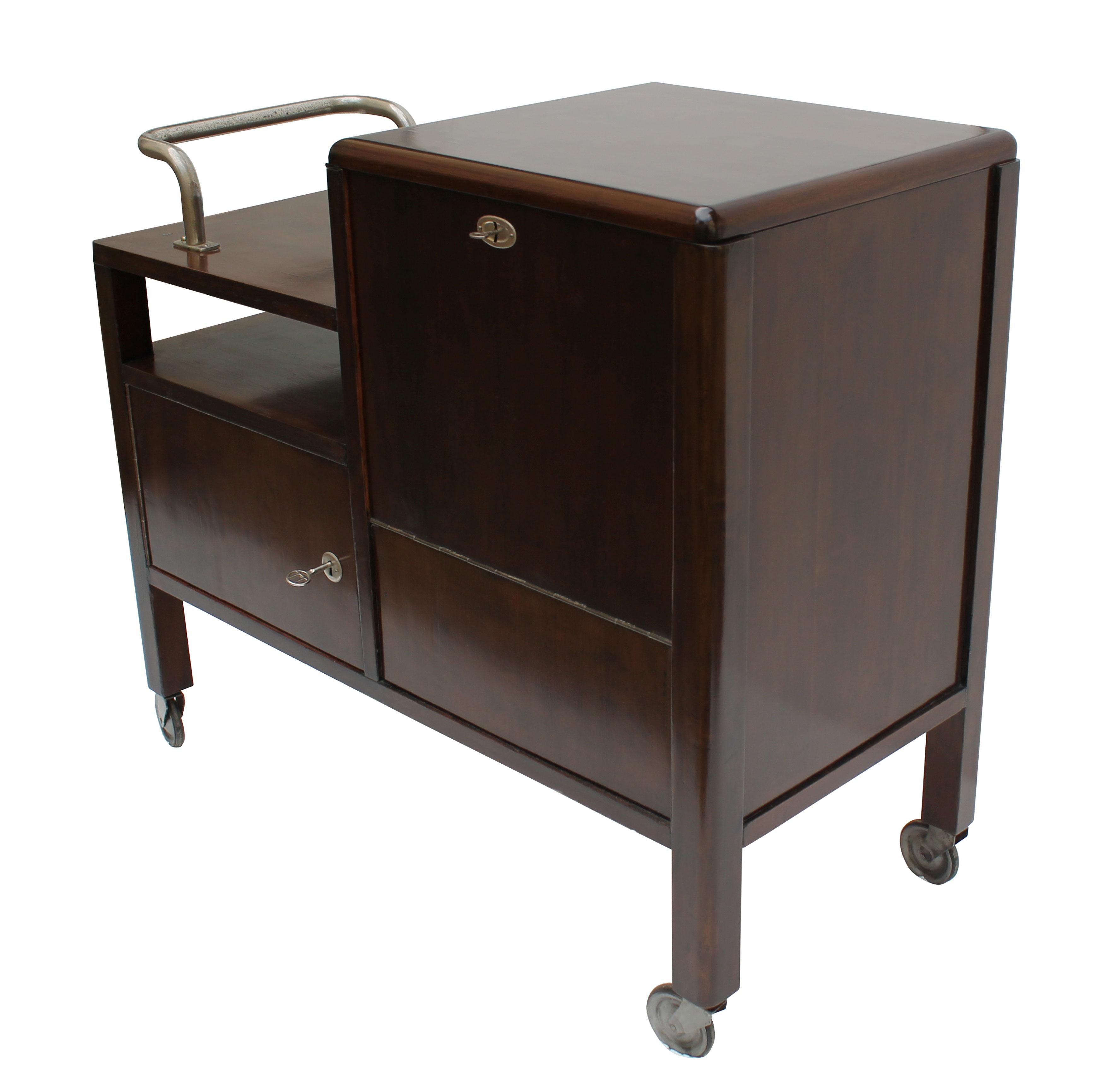 An original Modernist drinks cabinet from the 1930s. This piece has soft curves, a subtle pattern of the maple veneer and a minimal black opaxite glass. Internally, there is a lovely pop of colour with it’s bright red coloured wooden glass