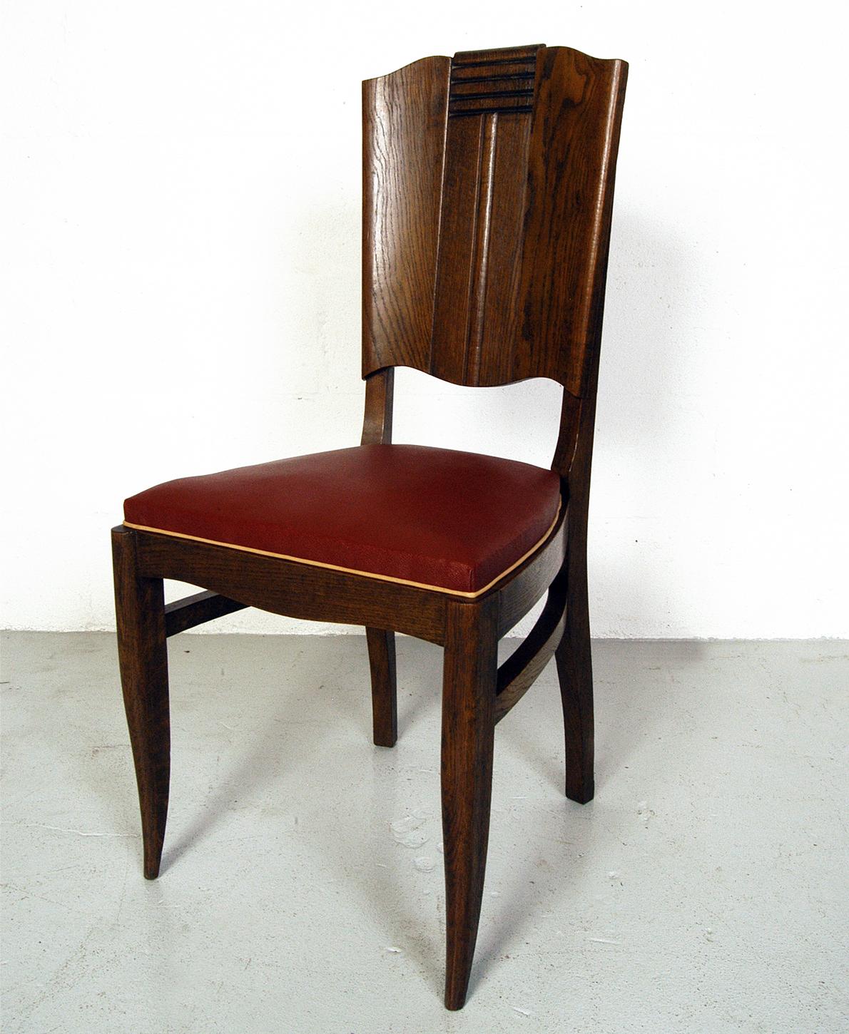 A magnificent set of six Modernist Art Deco dining chairs attributed to Charles Dudouyt in original period burgundy Rexine with cream piping. Carved oak detailing to the back and elegant modernist sabre-shape to the front legs. The seats are sprung