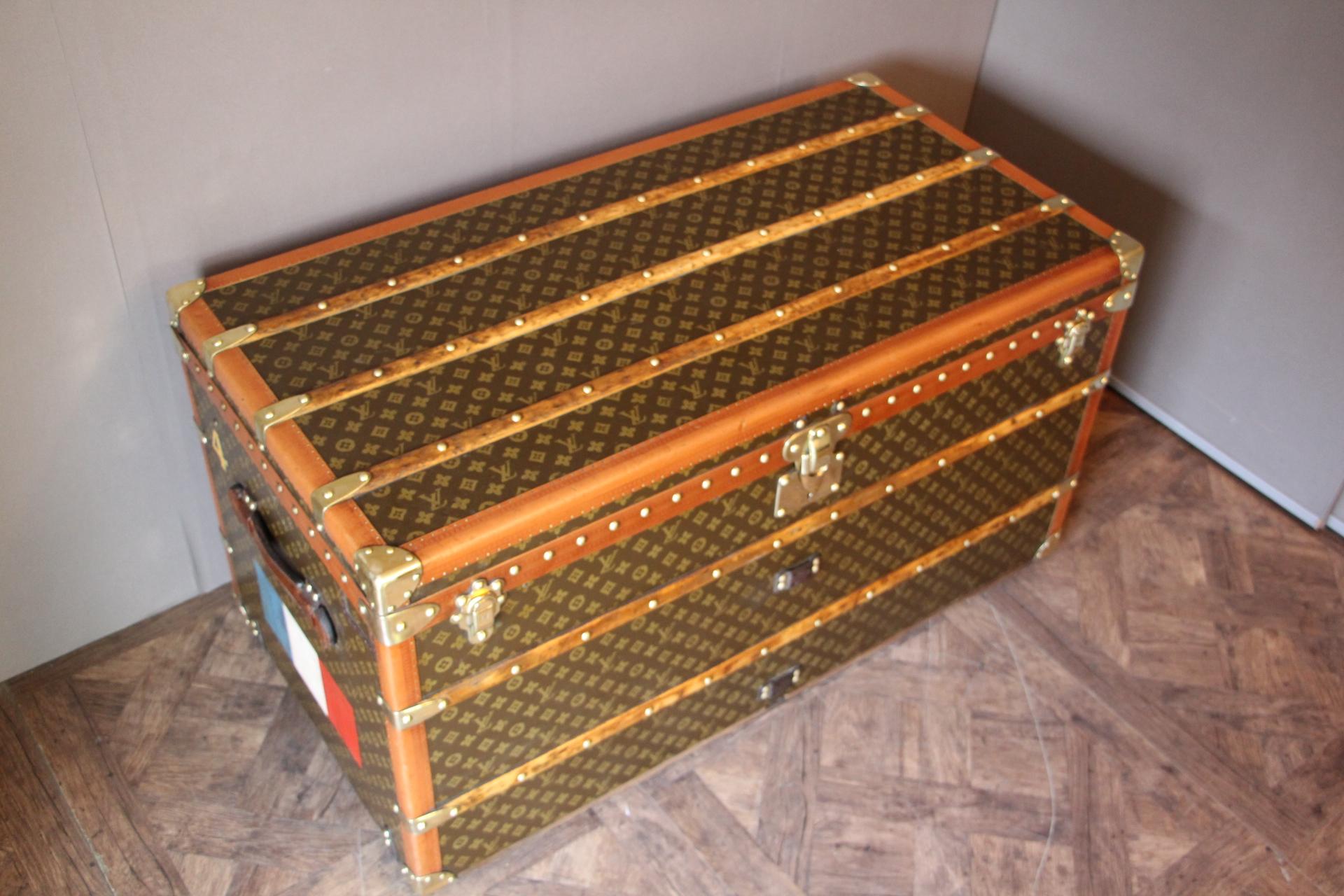 This beautiful Louis Vuitton trunk is all stenciled LV monogram canvas, with all Louis Vuitton stamped brass hardware and lozine trim. It features large leather side handles as well as a customized French flag on each side. It has got a very warm