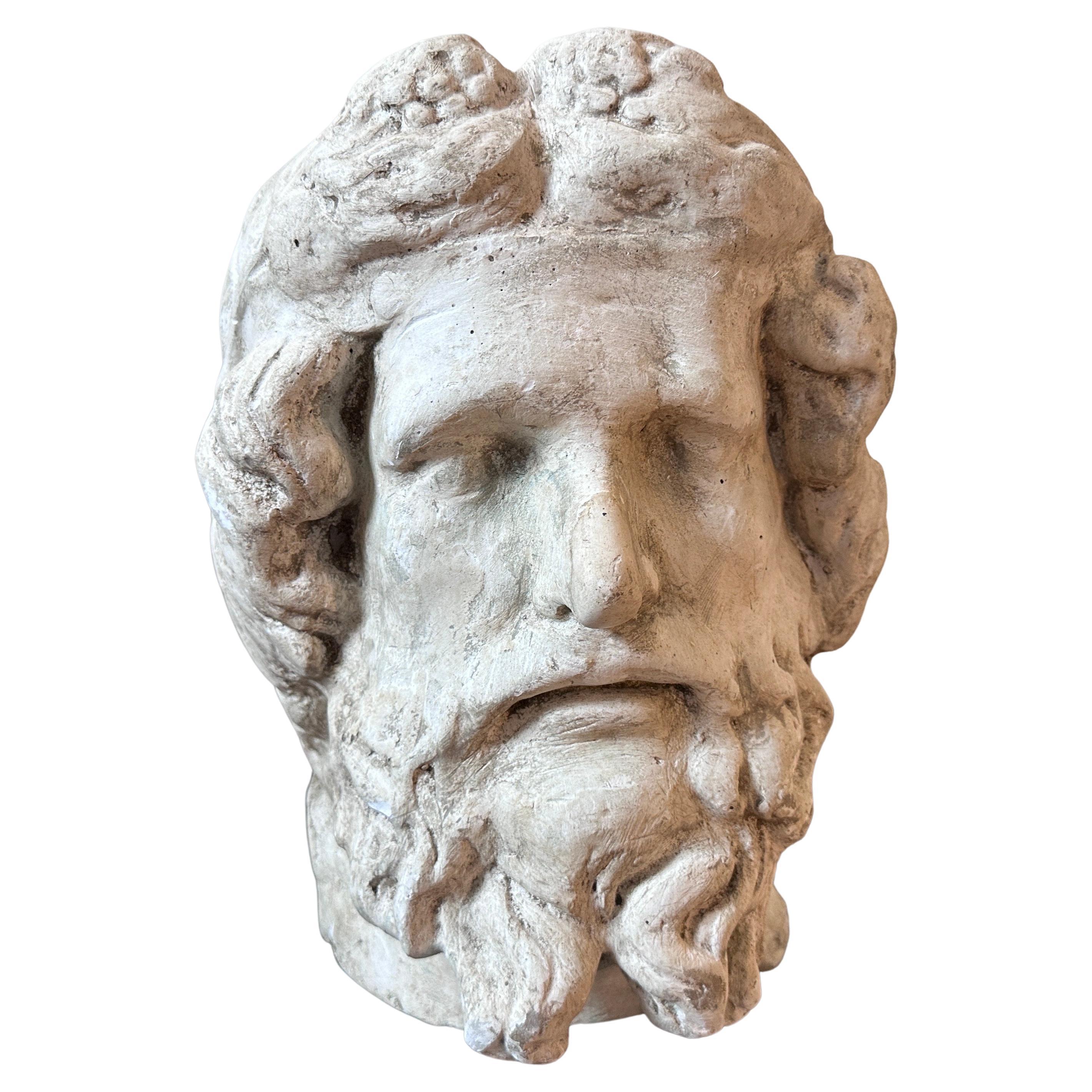 A Serapis plaster head hand-crafted in Italy by school art students in 1930s, it depicts the facial features and characteristics associated with this deity from ancient Egypt. The head showcases a bearded male figure with a serene expression,