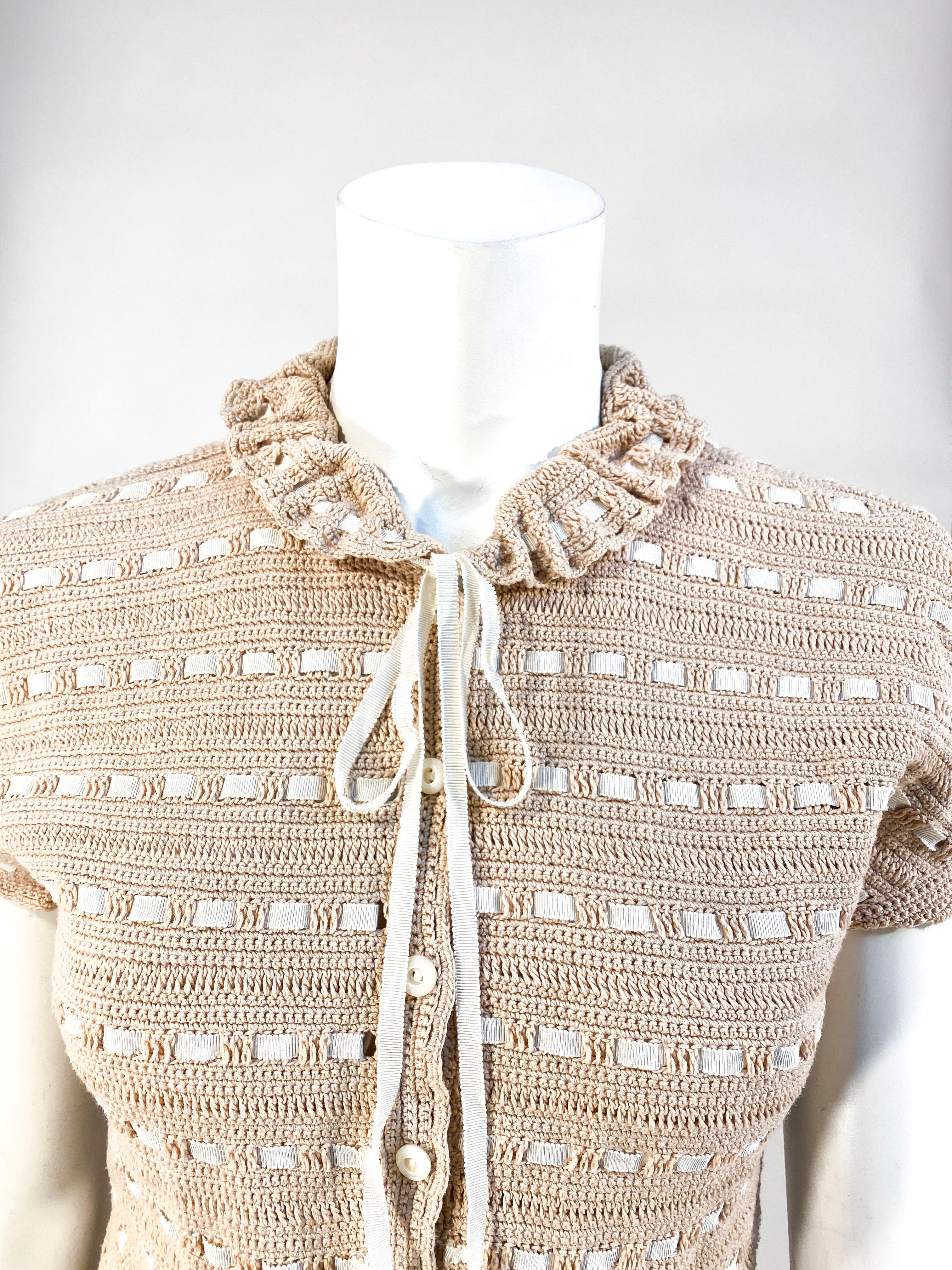 1930s Nougat-colored/l beige crochet sweater with cap sleeves, short applied gathered cuff, ruffled collar, grosgrain ribbon tie and woven alternating rows. The edges all around the sweater have small scalloped trim, the front closure has mother of