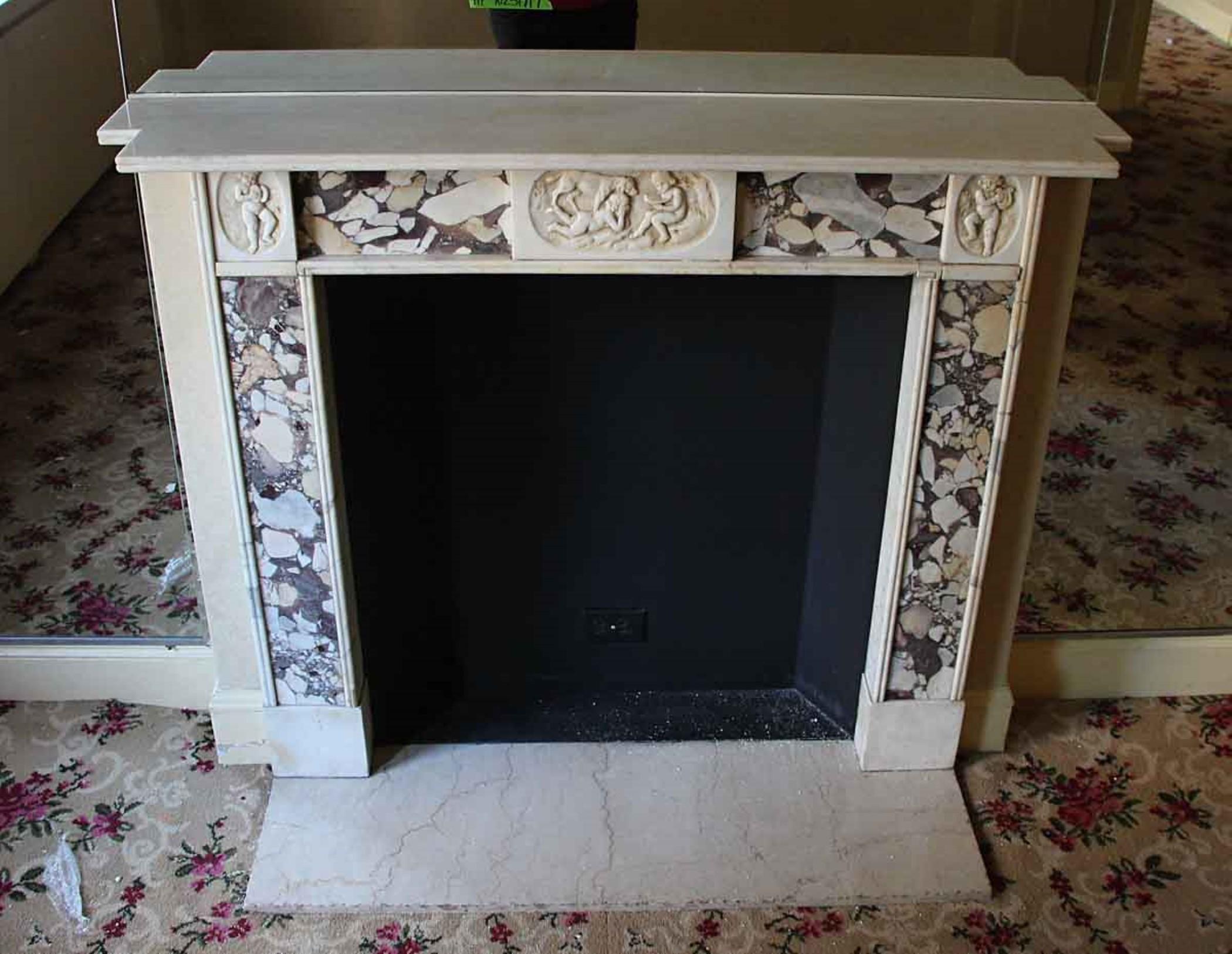 Early 20th century English Regency statuary and violet breche marble mantel. The marble is in good condition with charming details of cherubs playing with a dog and cherubs at each corner. This mantel was one of a group of antique mantels imported
