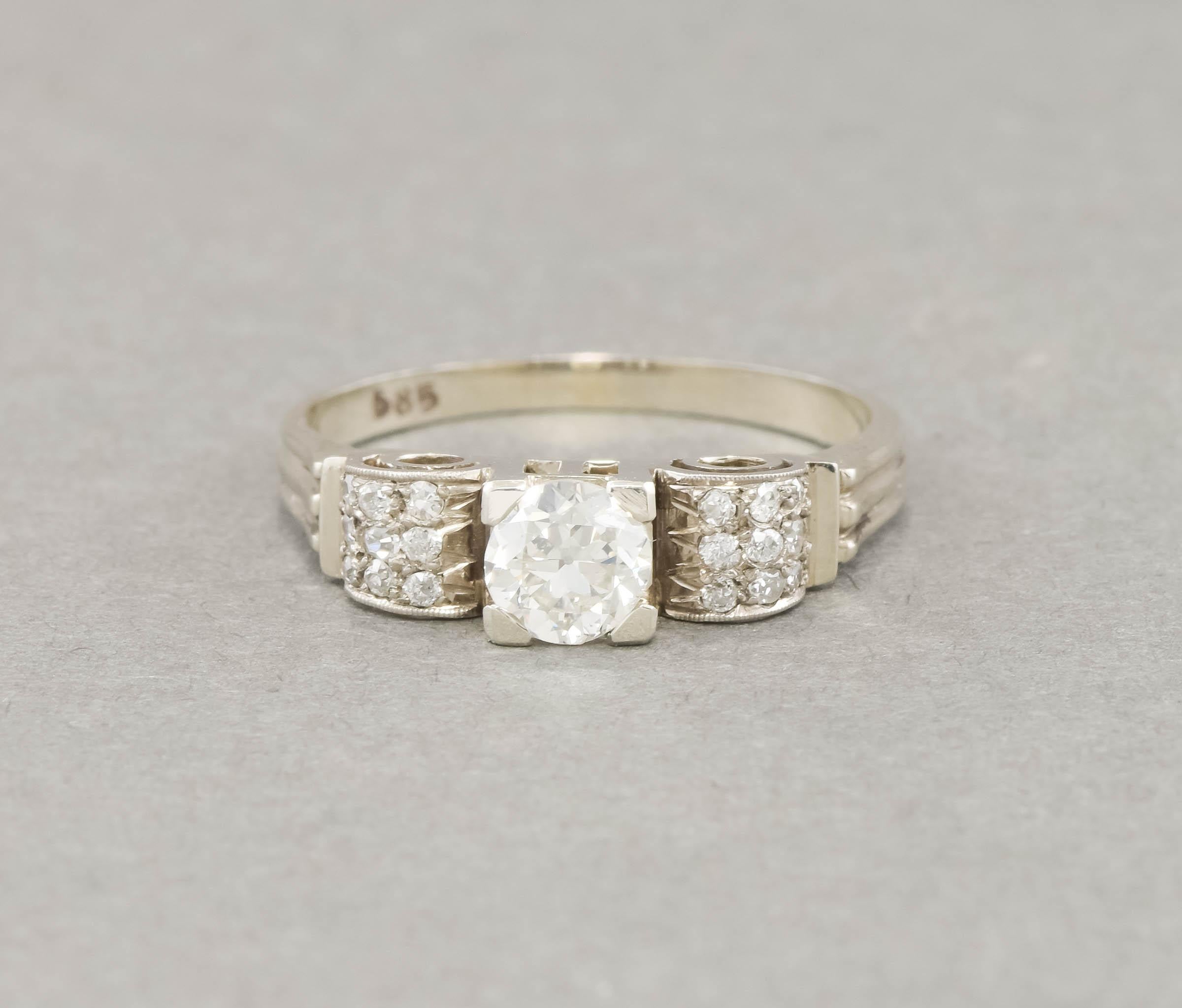 Made in Europe during the 1930's, this charming diamond engagement ring features an especially pretty European cut diamond amid a gracefully curving mounting of small accent diamonds.  (please note that dark areas in the diamonds are just