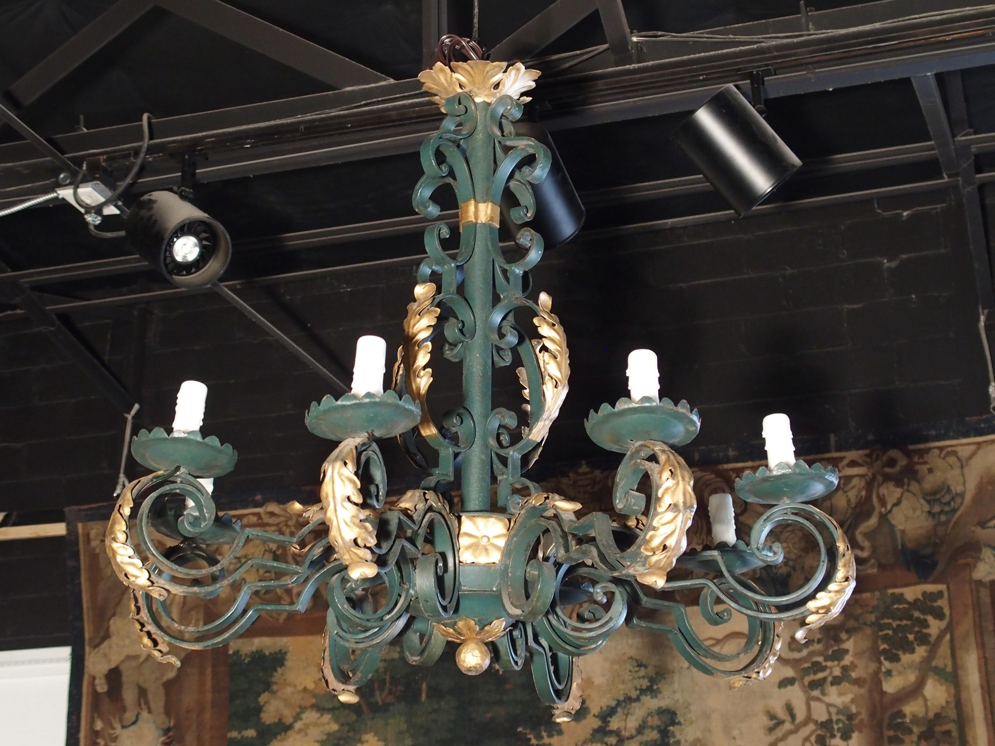 This graceful French eight-light chandelier is made of painted iron and gilt tole. The iron has been painted a medium forest green and the rest of the ornamentation is gilt tole. It is in the style of Louis XV and has acanthus leaves, C-scrolls and