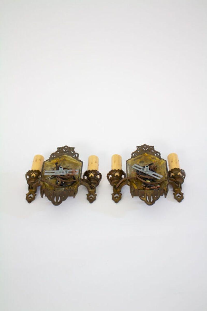 Art Deco two arm bronzed cast iron sconces. Switch on backplate. Art deco style. Design sits close to wall, can be used in smaller spaces, hallways or stairways.

Material: Iron,Paint
Style: Art Deco
Place of Origin: United States
Period Made: