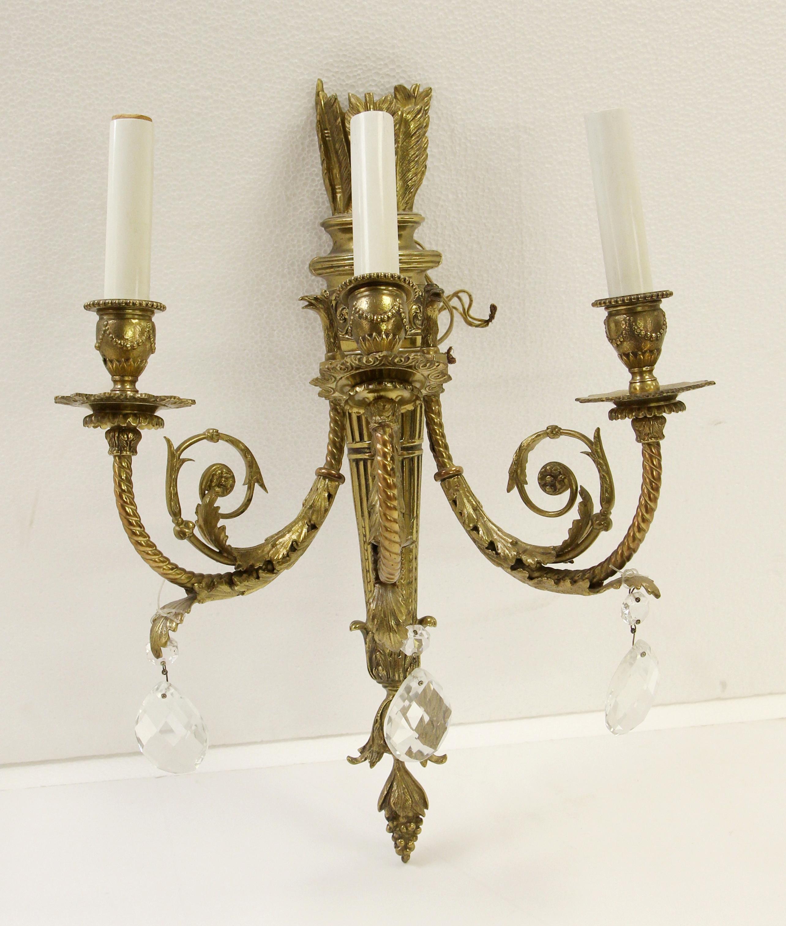 1930s pair of 3 arm highly ornate French style torche sconces. Made of brass with teardrop crystals on each arm. Original patina. Small quantity available at time of posting. Please inquire. Priced per pair. Please note, this item is located in our