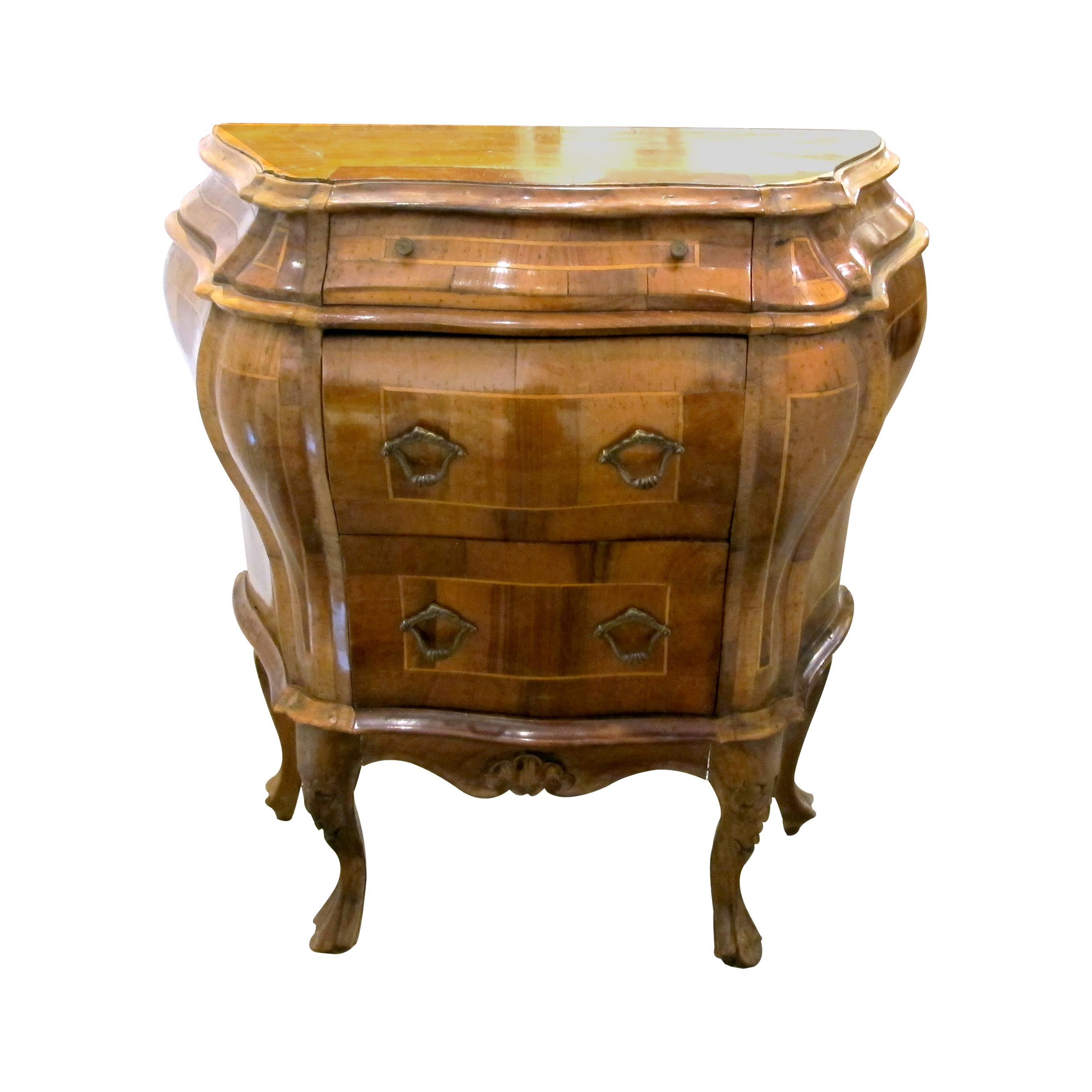 This is a pair of 1930s Italian bow-fronted Bombe side tables crafted from walnut and olive wood marquetry. The rich, curvy design is a hallmark of the Bombe style, giving each piece a robust yet elegant profile. Each table features three drawers: