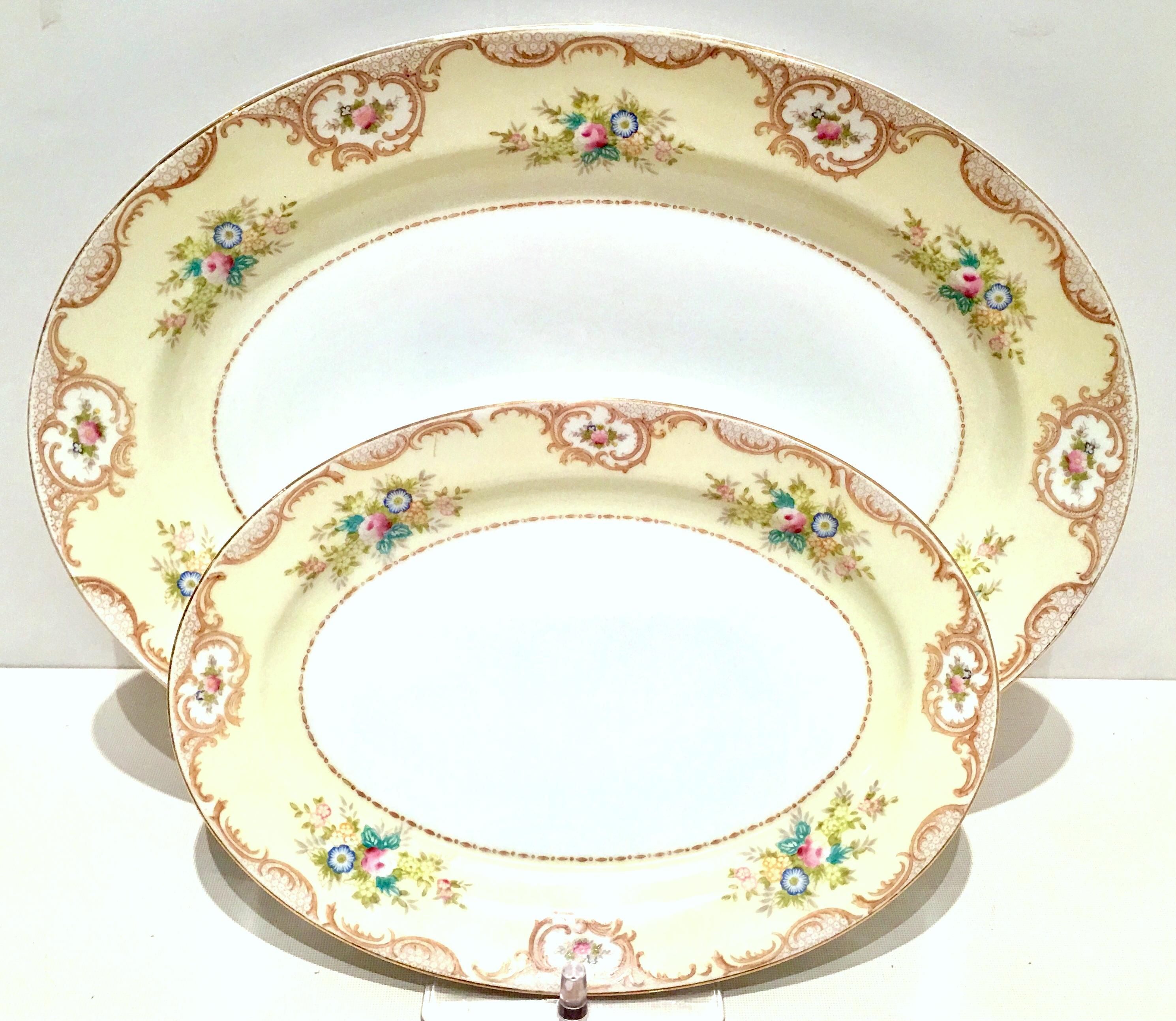 20th Century Pair Of Japanese porcelain hand-painted oval serving platters. Each piece features a white ground with a butter yellow border and Art Nouveau style floral and 22K-gold scroll pattern. Each piece has a 22-karat gold rim detail. Each
