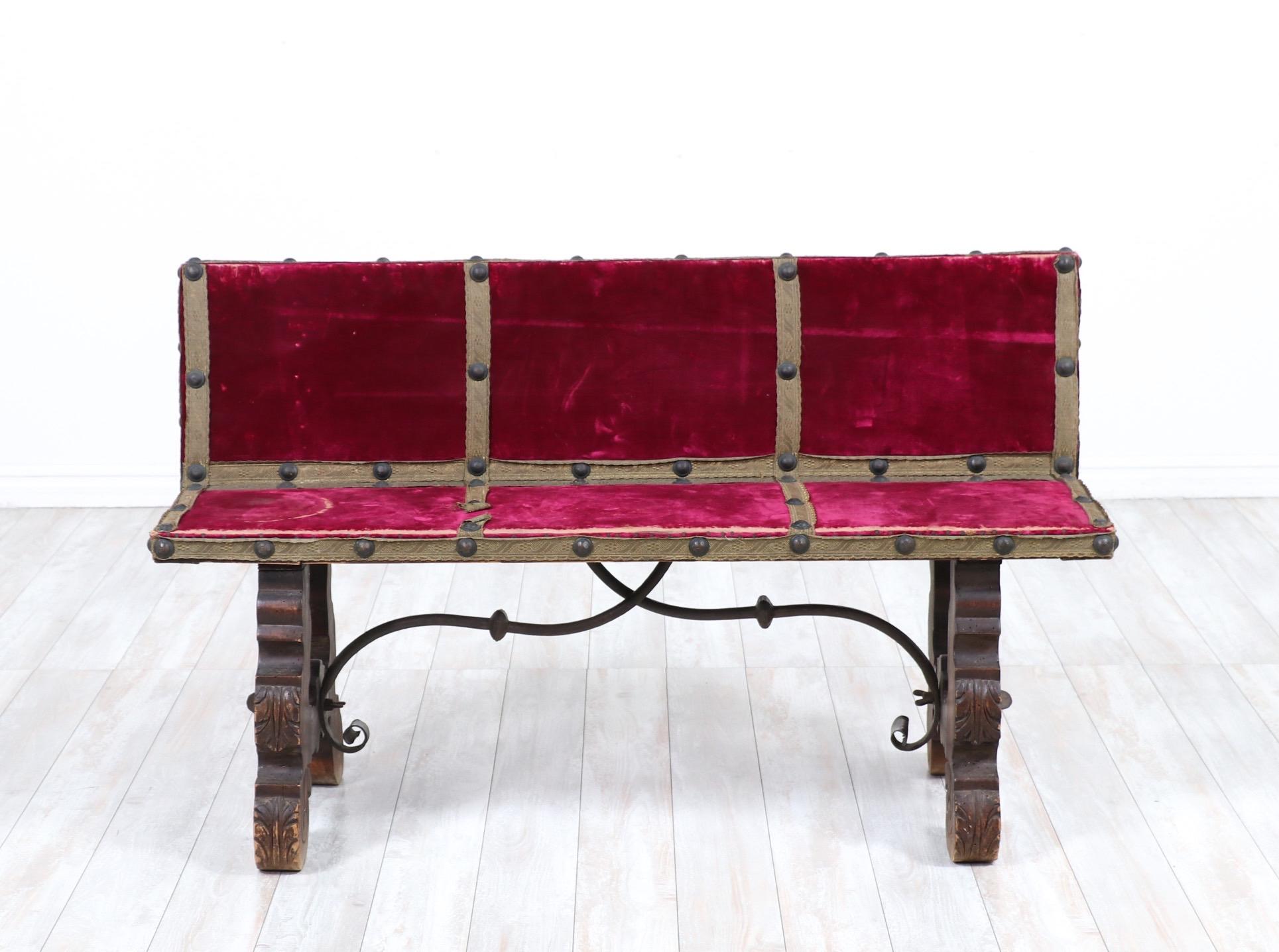 Petite-scale, 1930s Spanish upholstered bench in the Baroque style.

The bench consists of a carved walnut frame with original velvet upholstery and brass nailhead trim.

The wood finish and upholstery show wear consistent with age.

Perfect