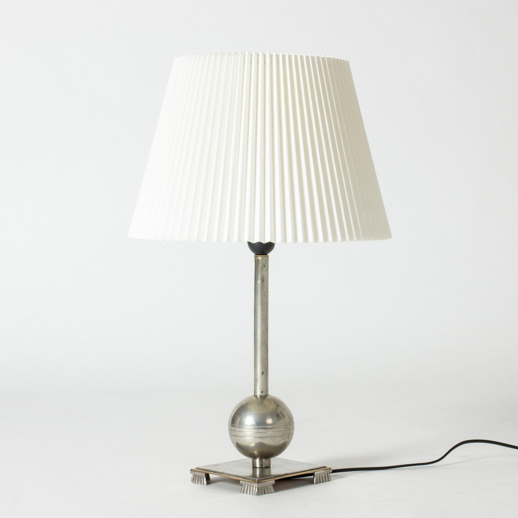 Elegant pewter table lamp by Einar Bäckström, in a functionalist design with a square base with decorative feet, and a globe on the handle.