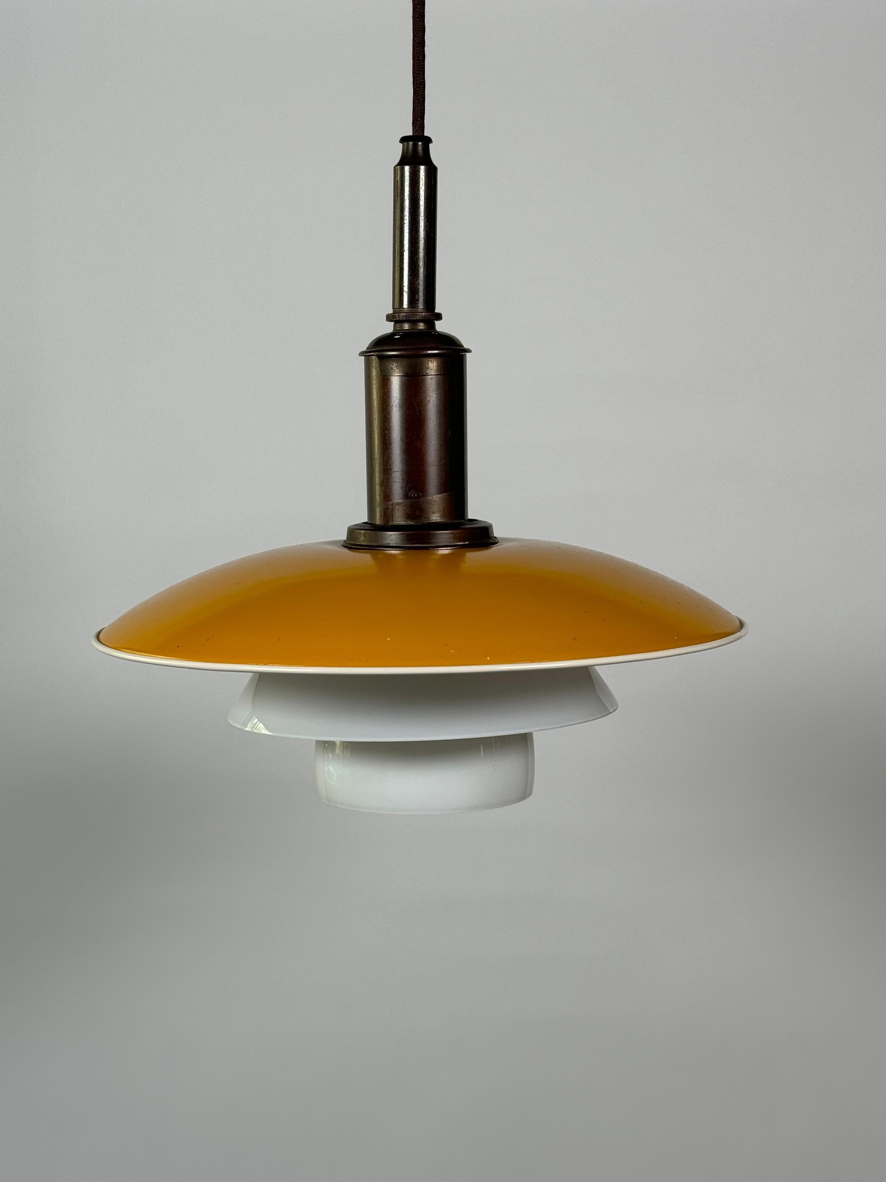 Poul Henningsen 3/2 Pendelleuchte aus den frühen 1930er Jahren für Louis Poulsen & Co. aus Dänemark. Kupfer- und Glaskonstruktion, oberer Schirm aus lackiertem, senffarbenem Kupfer, die beiden unteren Schirme aus weißem Glas, der Rest der Leuchte