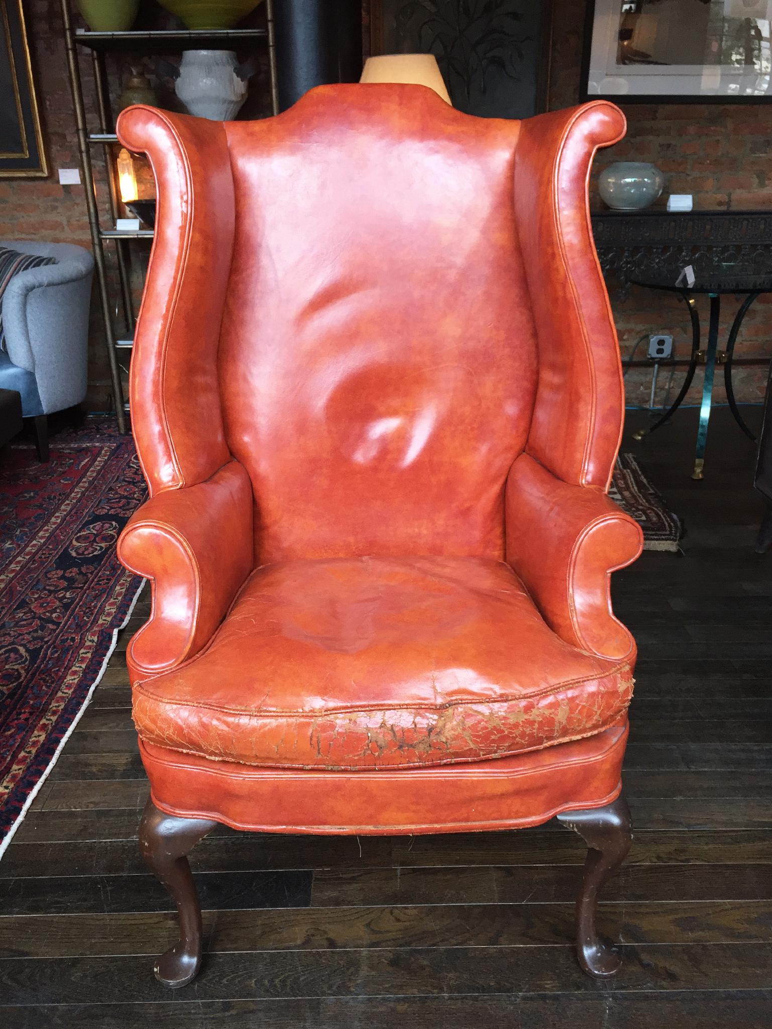 This stunning English wingback was made in the 1930s. It is in the Queen Anne style and is comprised of leather upholstery and mahogany legs. The leather is a rich caramel color. It is beautifully worn, a look that bestows the chair with alluring