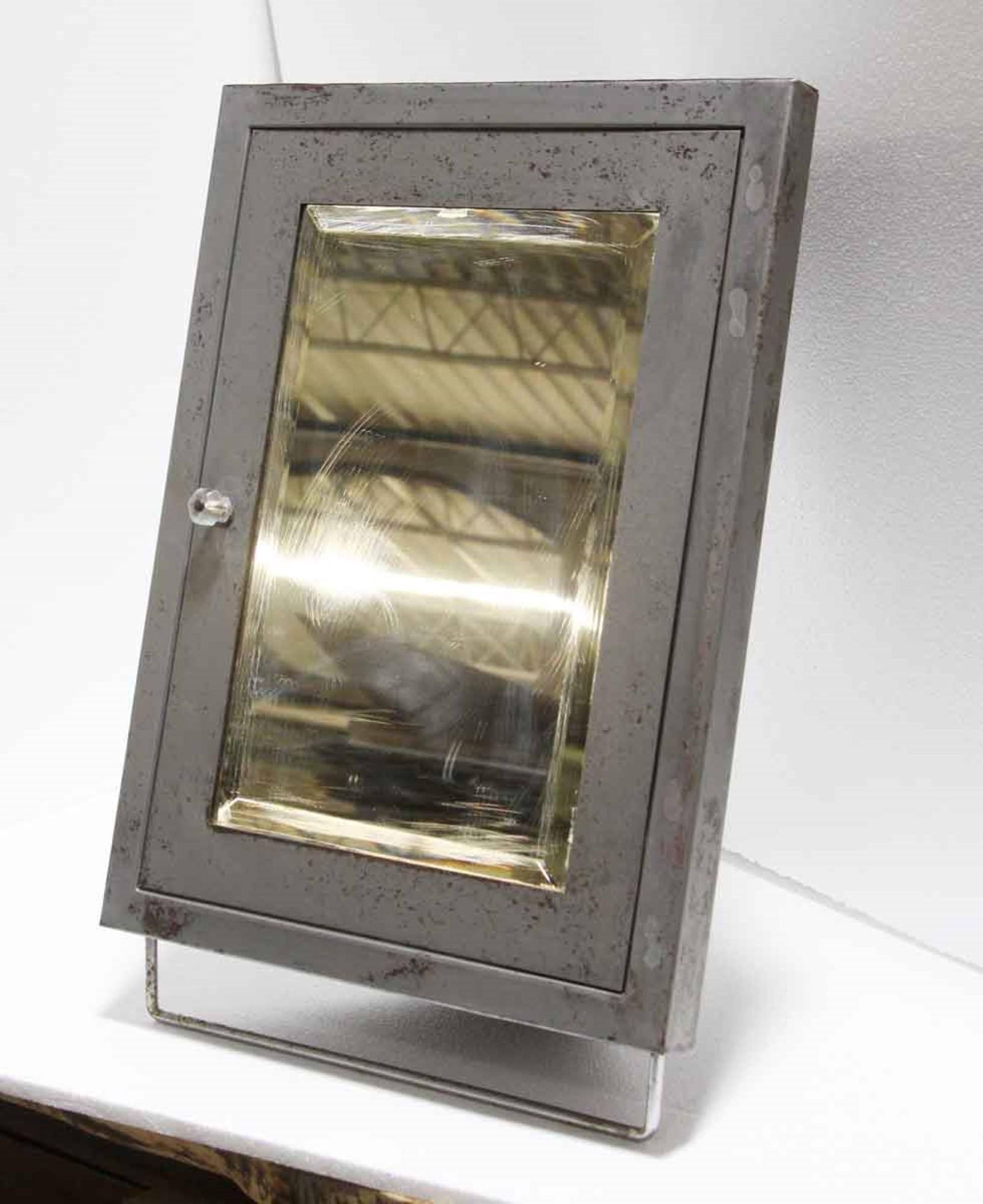 These are rare, hard to find corner medicine cabinets for a tiny bathroom. Made of steel with two shelves and a towel bar below, along with a beveled mirror. Each cabinet has a single antique glass pull. Stripped and sealed with clear lacquer. Small