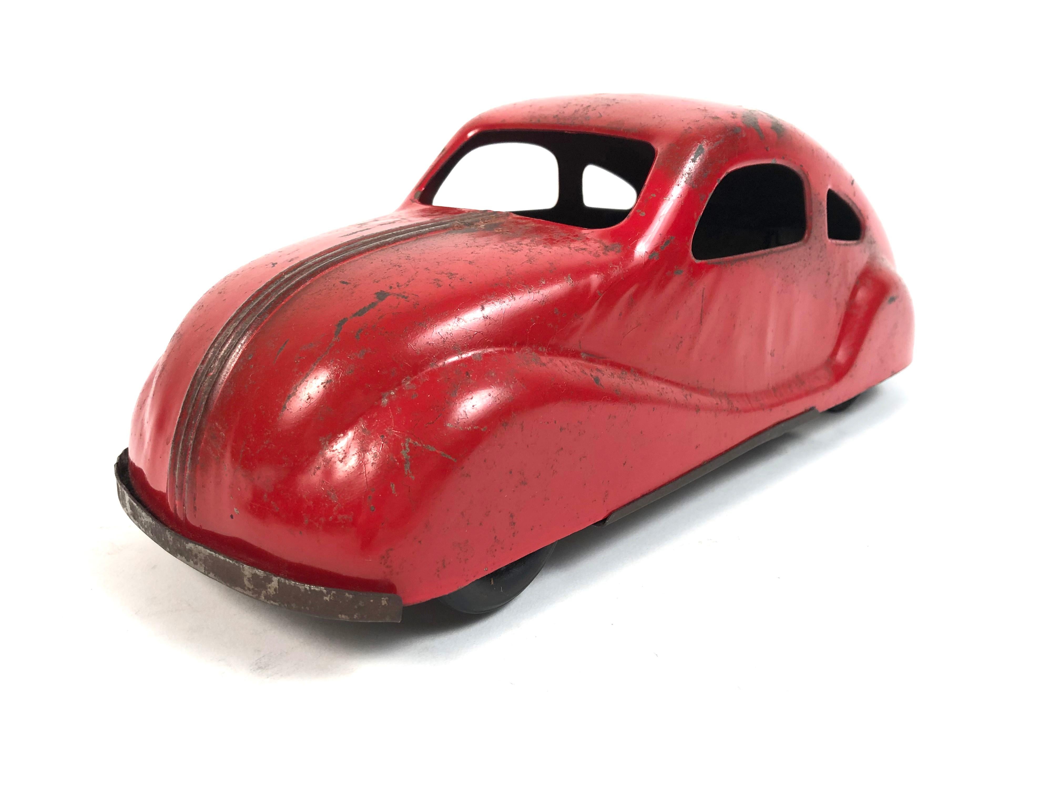 A sleek, streamlined 930s red painted pressed tin toy car by Wyandotte, (Michigan). Greta lines and retaining its original red painted surface.