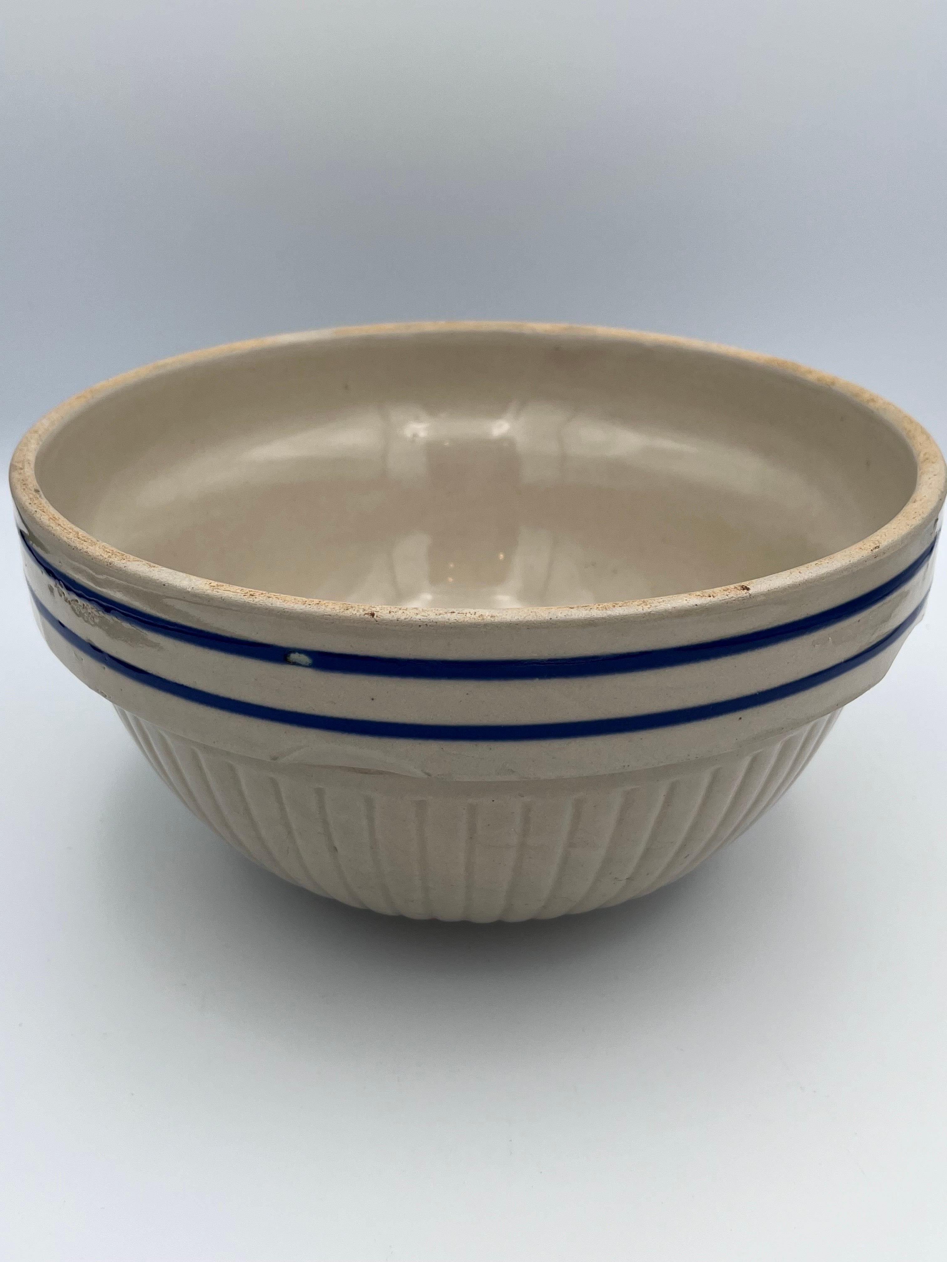 This substantial 1930s Red Wing mixing or serving bowl is a classic example of early American utilitarian stoneware. Finished in a warm tan glaze with two vivid cobalt blue bands, the bowl reflects the understated elegance and practical beauty of