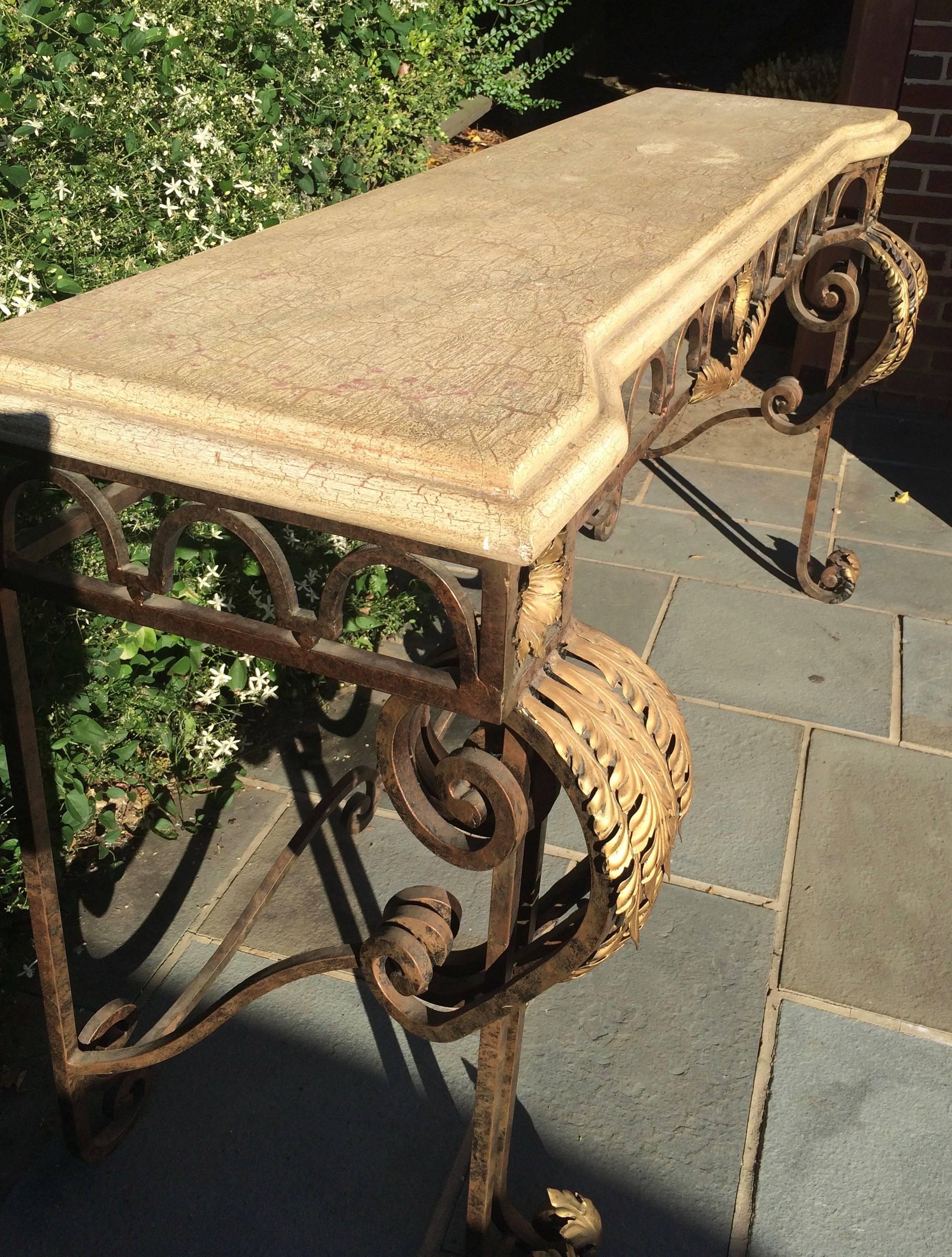 Large “Regence” style French Provincial console table made of forged steel with an inverted serpentine faux marble top over boldly shaped cabriole legs. Beautiful flowing lines with great craftsmanship of gilded sunflower and leaf motif above a