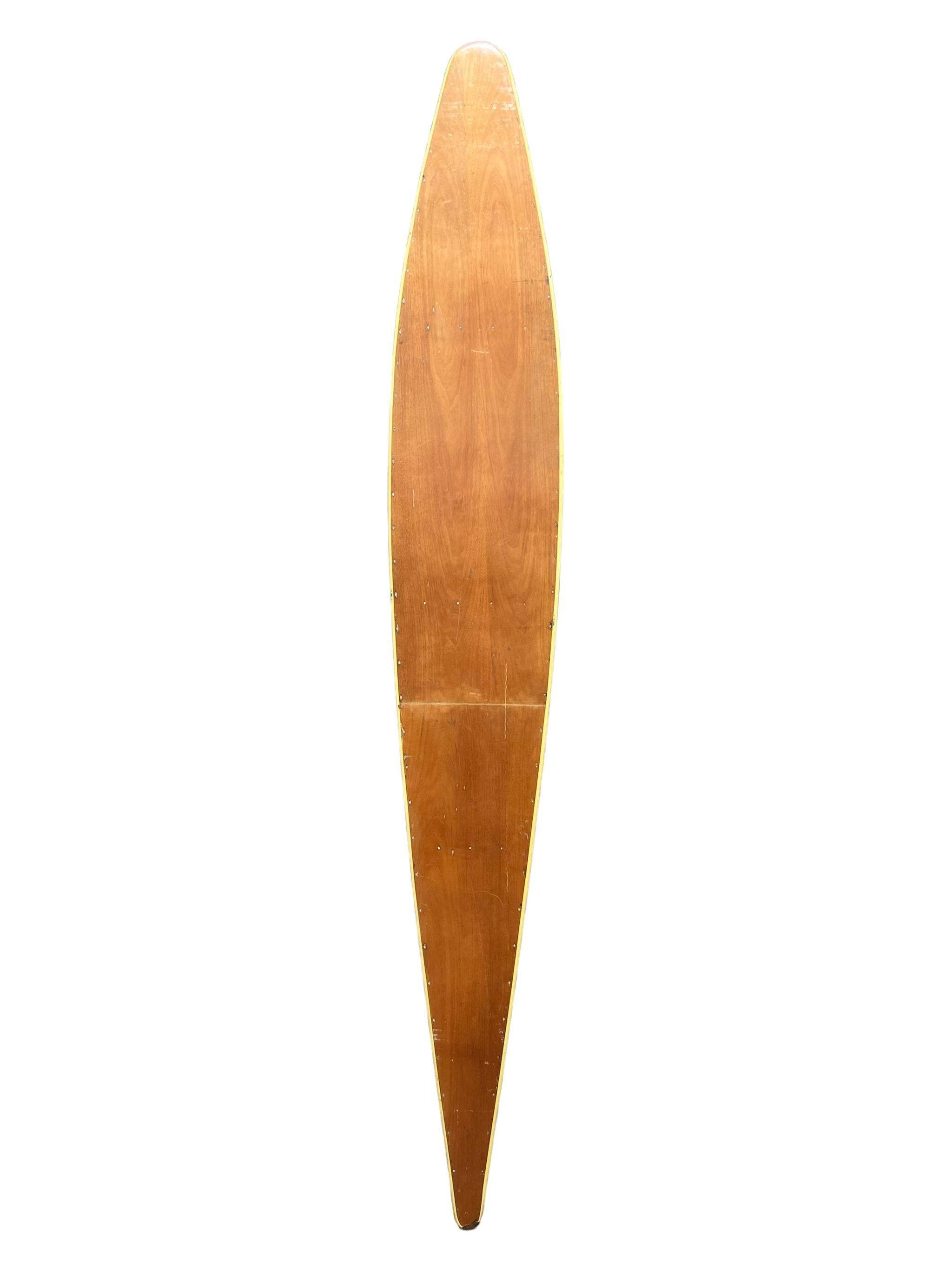 1930s Replica Tom Blake hollow wooden surfboard. Wooden panels joined by metallic fasteners with daffodil yellow outline. Patented by the late Tom Blake (1902-1994) in 1931. The interior ribbed design was modeled after the airplane wing, allowing