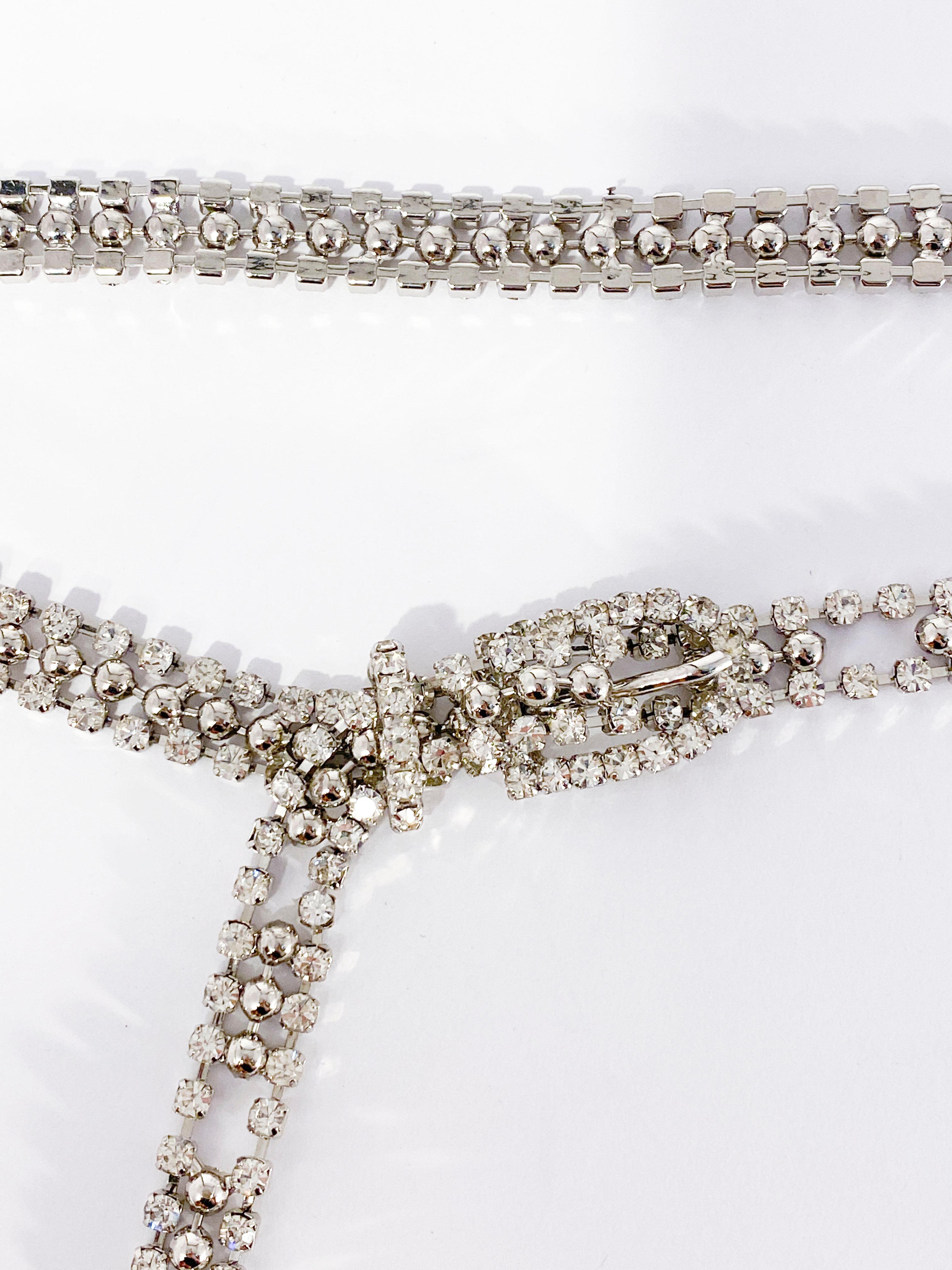 1930s clear rhinestone belt set in a silver-tone and accented with a studded center strand. The built in belt buckle is made of set rhinestones along with the tail and the keeper of the belt. The belt holes accommodate sizes from a 27 inch-waist to