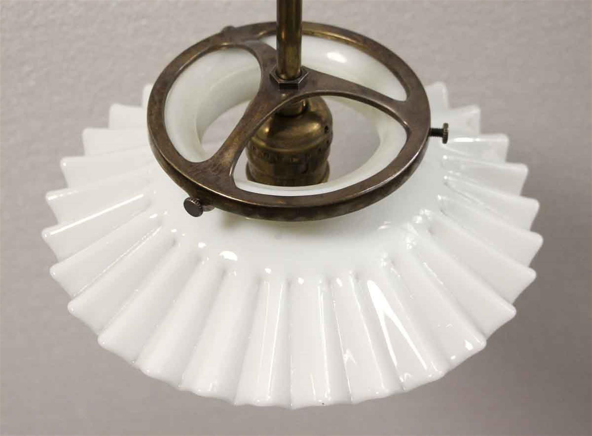 Single bulb ruffled white milk glass pendant fixture from the 1930s. The shade is vintage paired with a replica pole in an antique brass finish. Small quantity available at time of posting. Priced each. This can be seen at our 400 Gilligan St