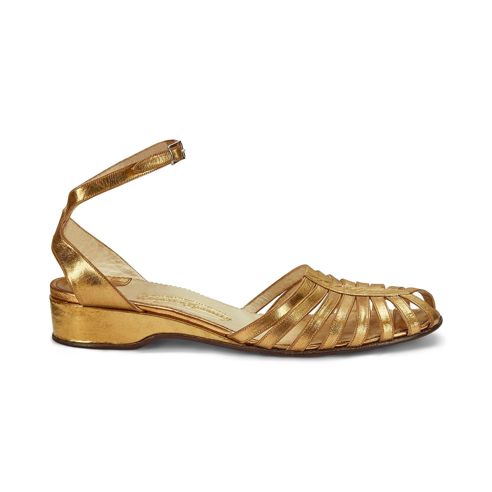 These striking strappy sandals were designed by classic British label Russell and Bromley. Founded in 1873, the debossed gold label dates these shoes back to the late 1930s. Crafted from a rich gold and lined with off-white leather, these sandals
