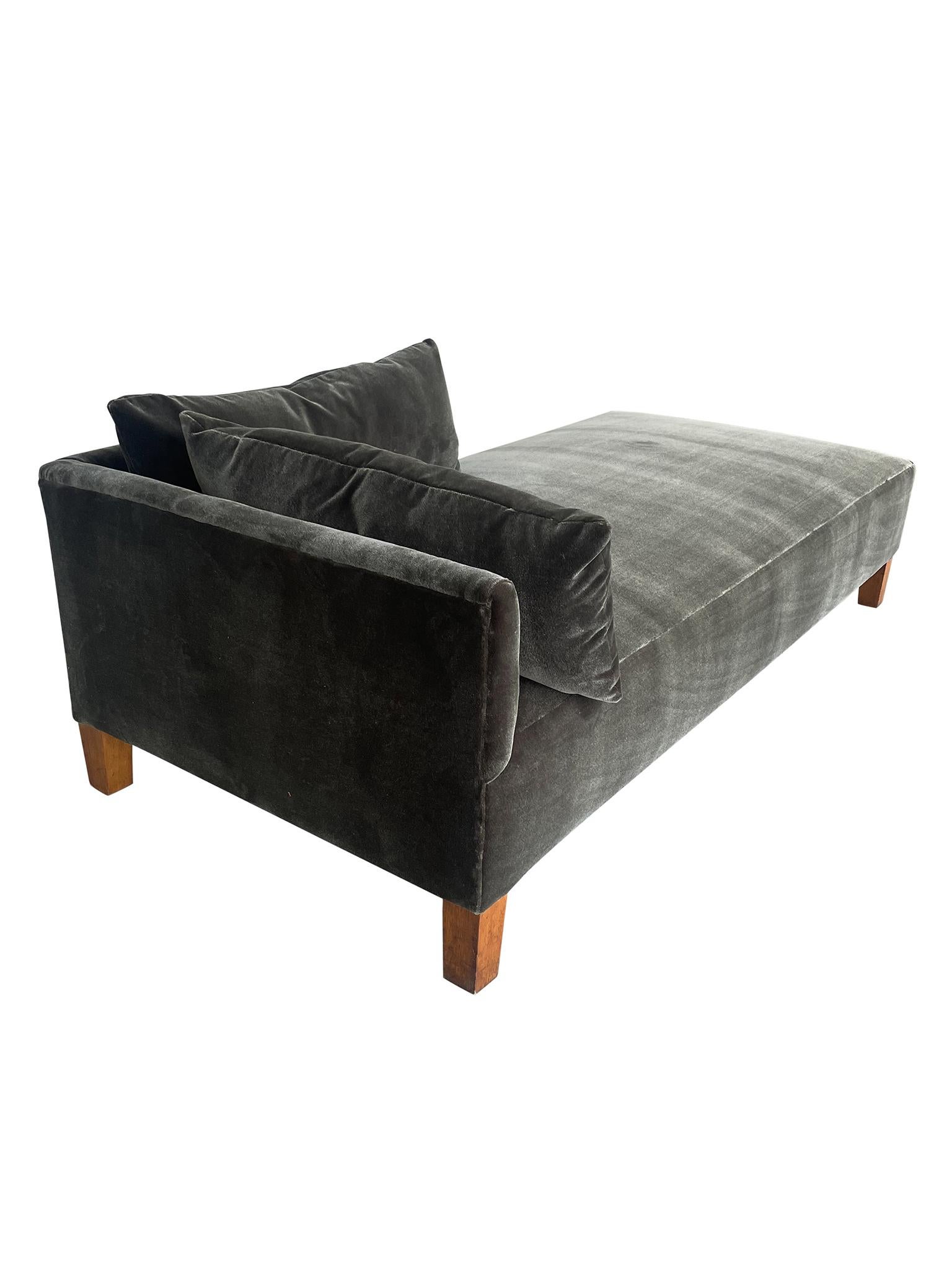 Lovely c. 1930s Scandinavian Modern Daybed. Designed with modern solid oak tapered legs, this sleek daybed features a low two sided head rest and a comfortable seat cushion. With new reupholstery and two custom cushions in a luxurious pewter green