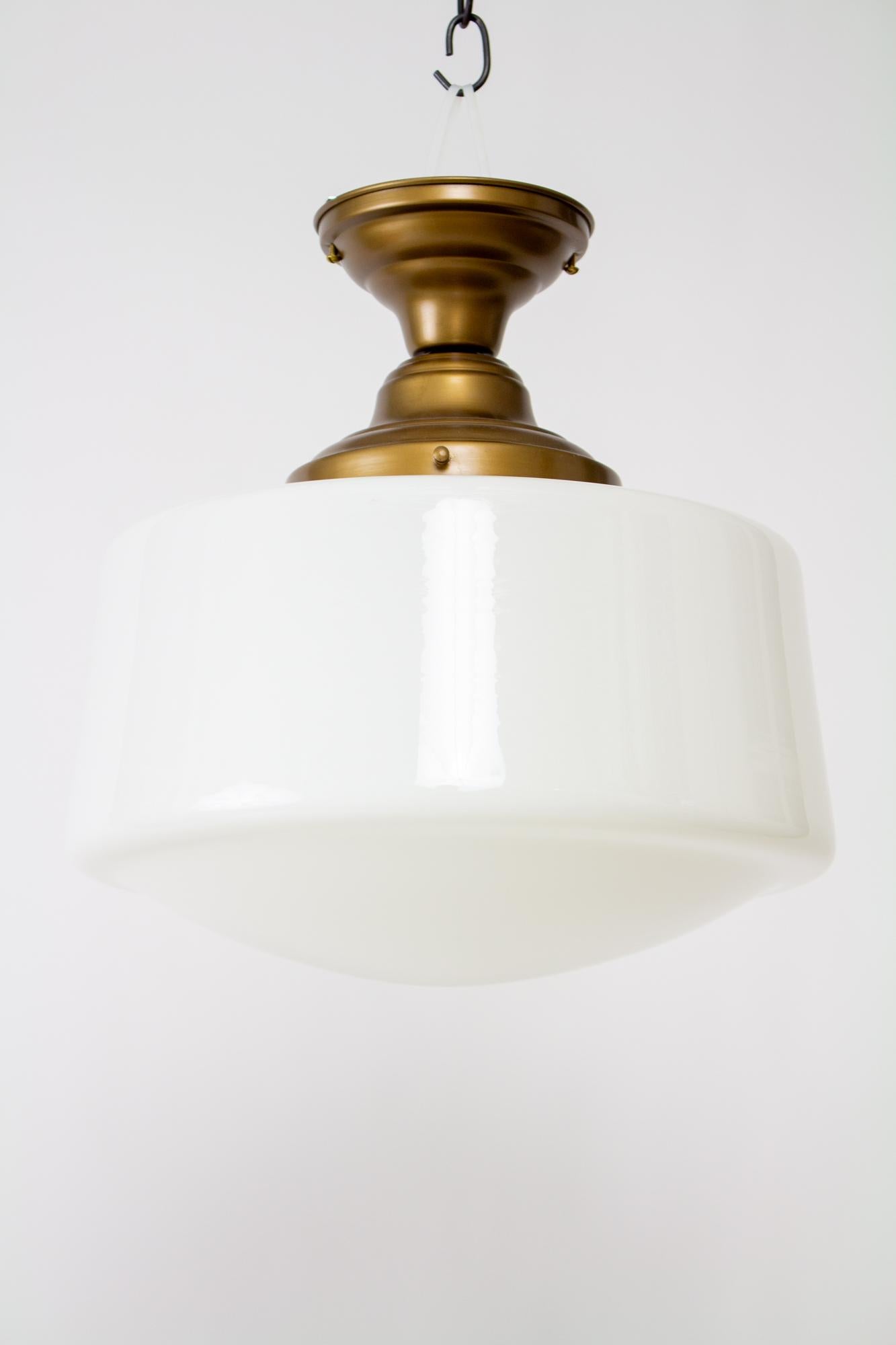 1930’s schoolhouse milk glass flush mount fixture. Glass is a variation of the traditional schoolhouse shade style. Mounted on a new fixture, satin antique brass finish , UL listed, with porcelain sockets. Excellent for a hallway or ceiling, and