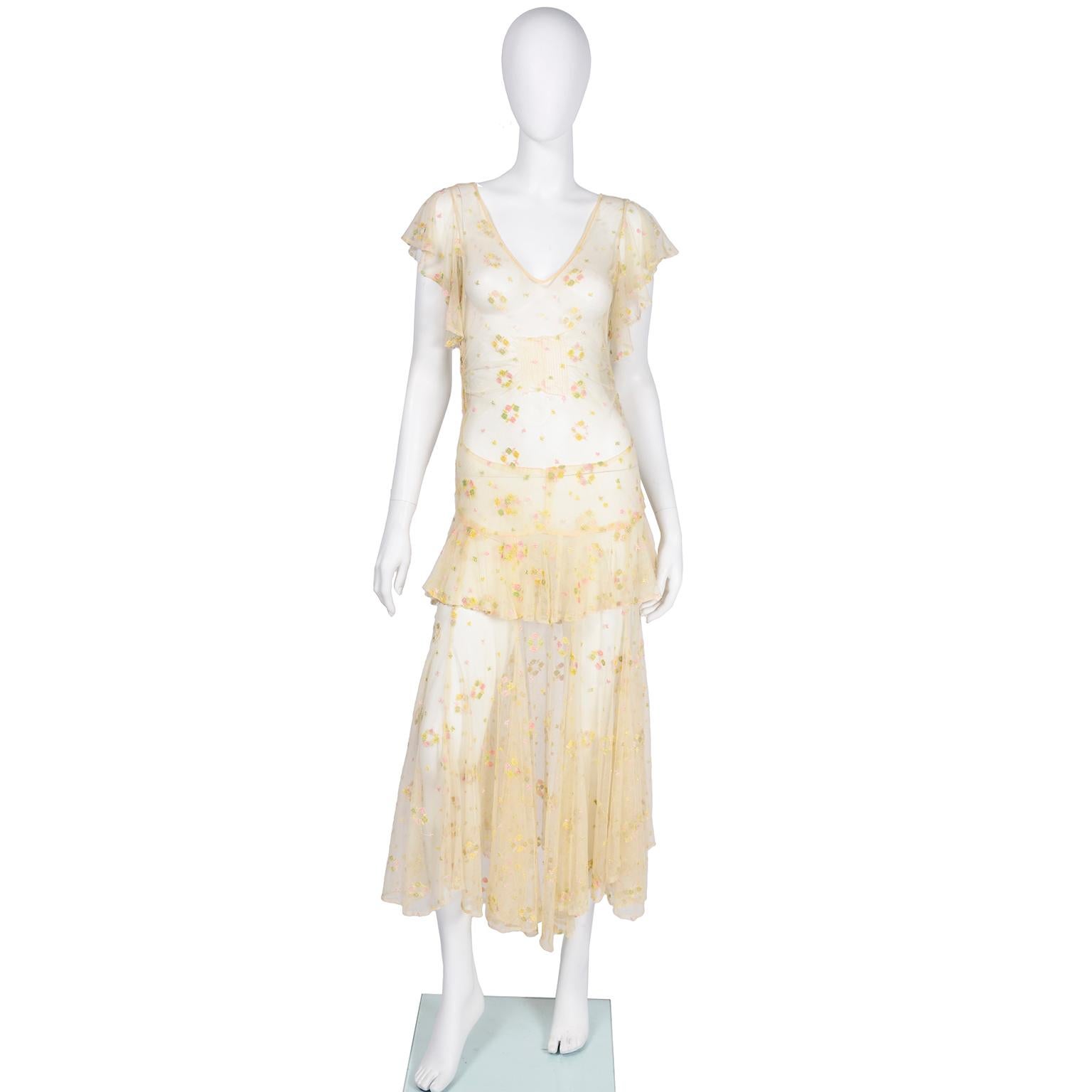 This dress is so incredible! It is made of a sheer creamy beige rayon or silk net with pastel embroidered flowers throughout dress. The  embroidery is various shades of pink, yellow, and gree and the dress has butterfly sleeves, a. V-neck and ribbed