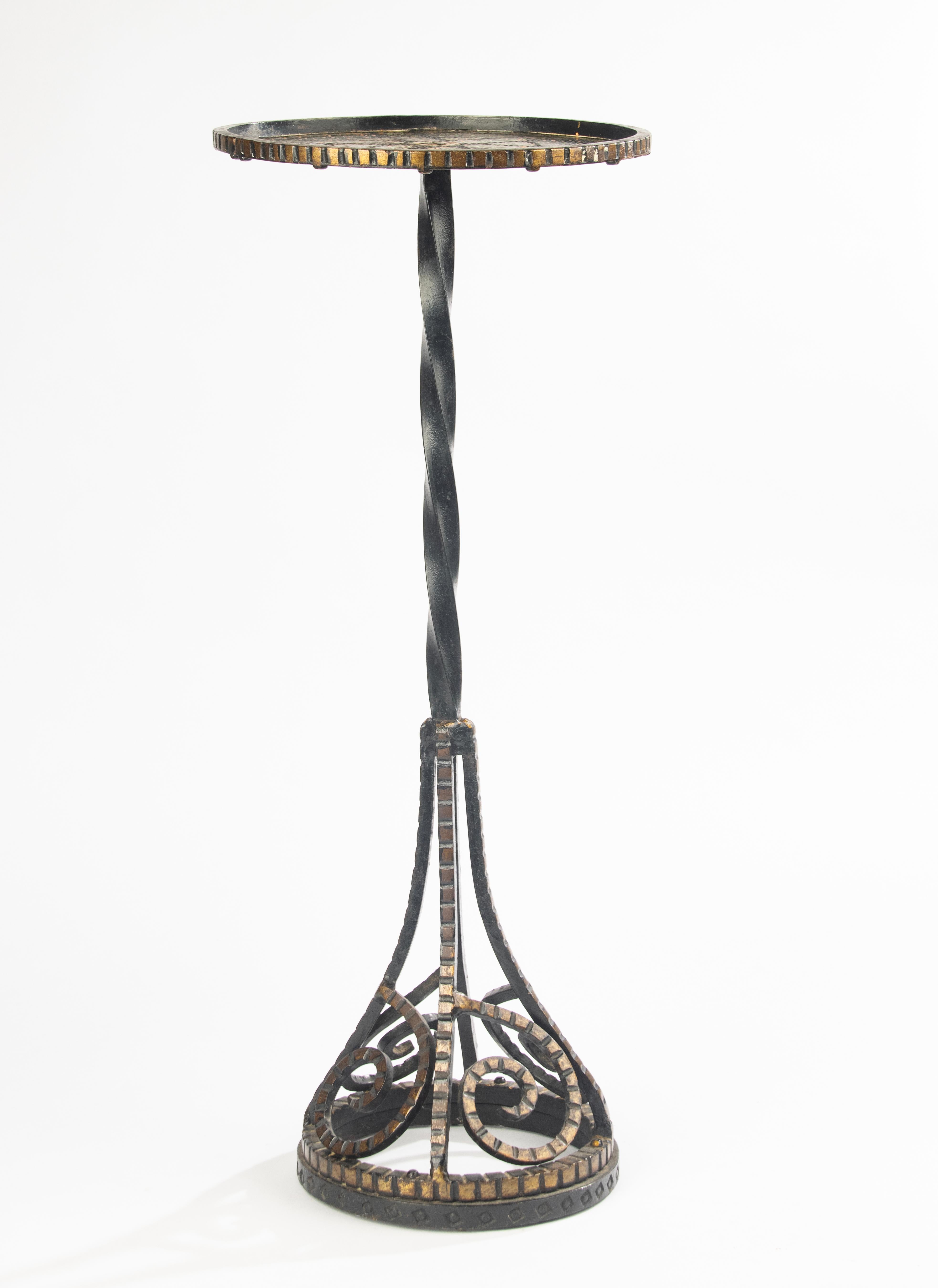 Elegant and slender Art Deco side table from France, circa 1930.
Made of hammered wrought iron with finely painted decoration in shades of gold, green and copper. The twisted stem and scrolled openwork base give it both stability and a refined