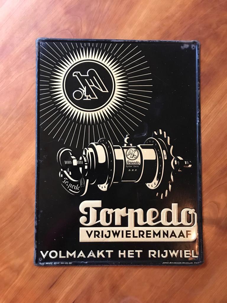 1930s Sign for bicycle parts. 
An Art Deco sign dated 1937. 
Black advertising sign with soft yellow embossed lettering and design for Torpedo Bicycle Wheel Brake Naves.
Tin sign - metal sign made in Belgium by the Company Jofico Brussels.
A Belgian