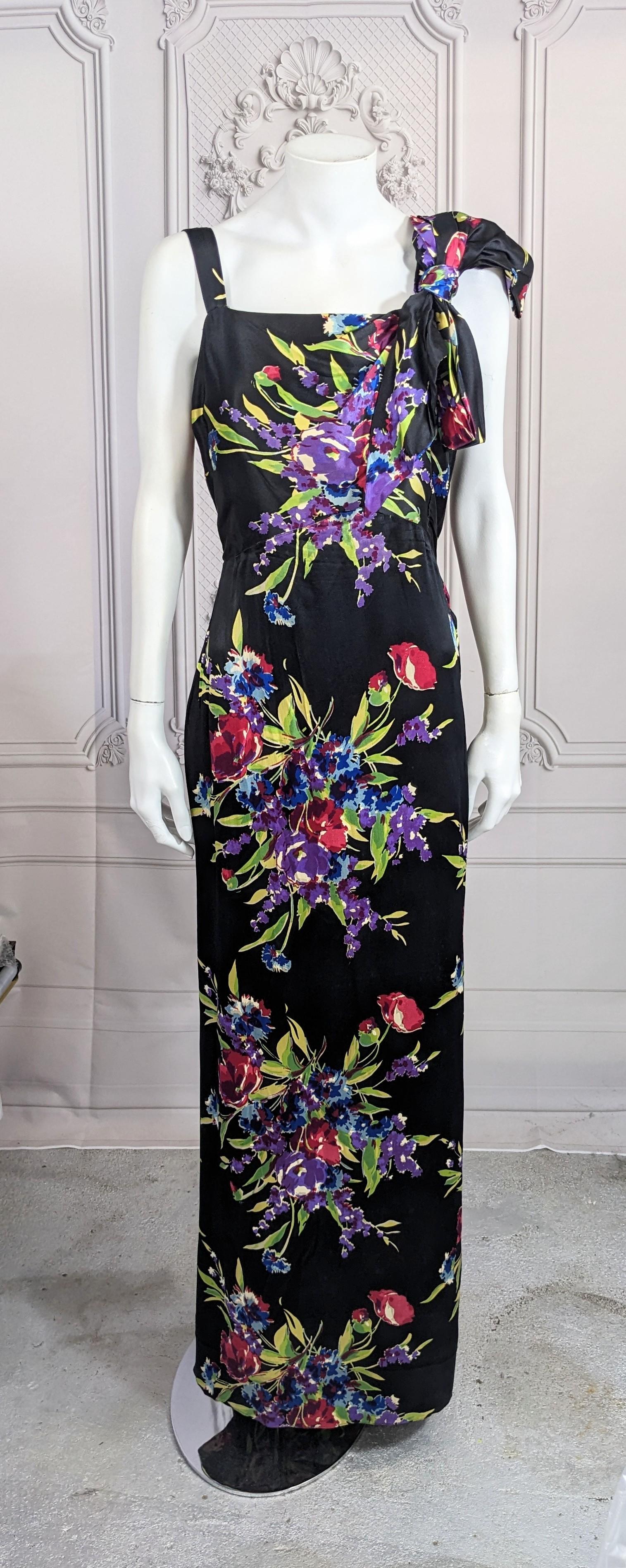 1930's Silk Satin Floral Gown made of Paul Poiret Designed Textile. Elegant design with draped bodice caught up into a large bow on left shouder. Simple straight cut with a circular panel on back skirt forming a small train. Side snap closures and 2