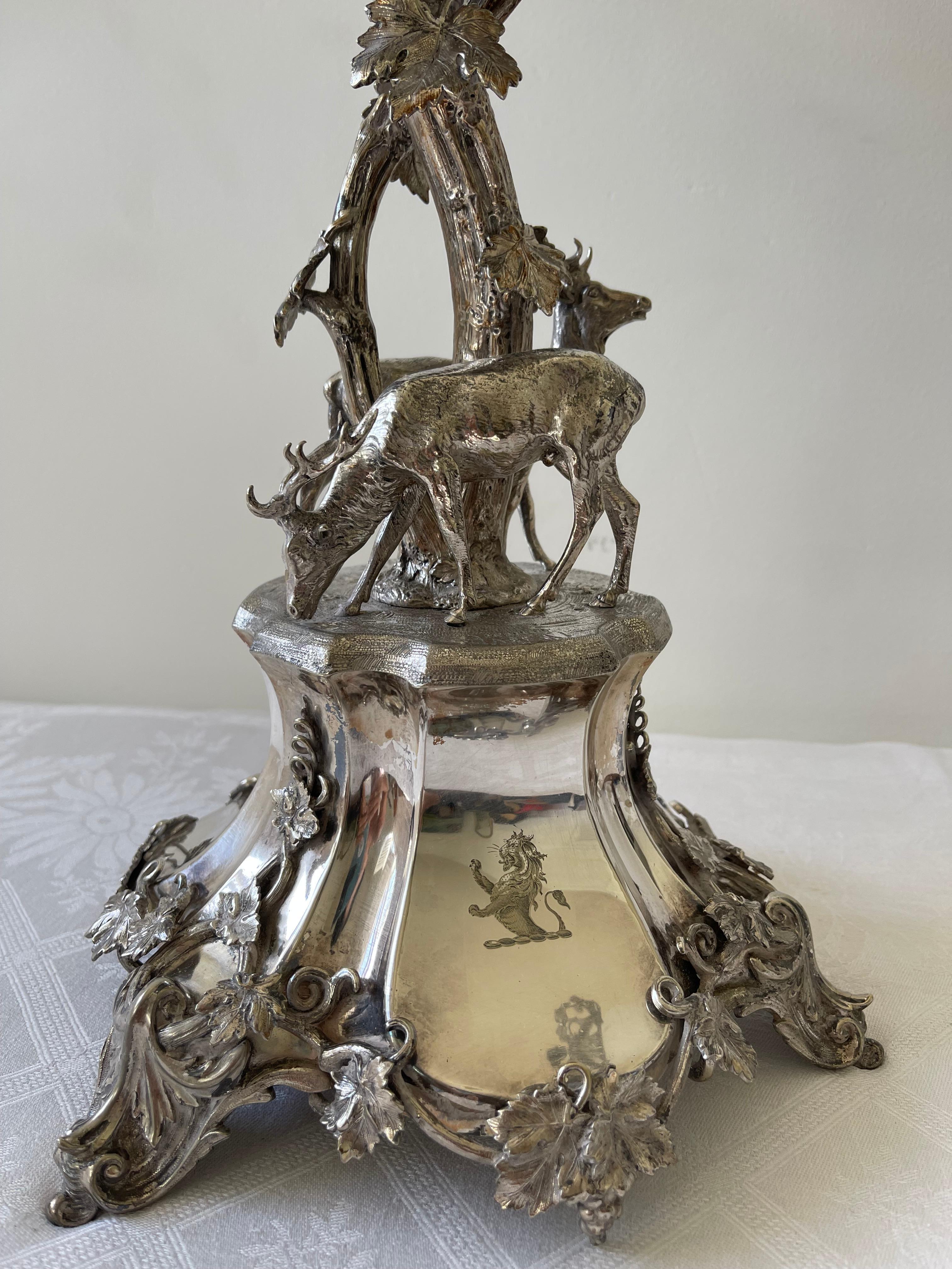 Beautiful decorative object with notable dimensions of naturalistic style.
This central piece with a thick base lined with foliage where two young deer rest. Thick branches with foliage and grape clusters are richly represented. Four trays can be
