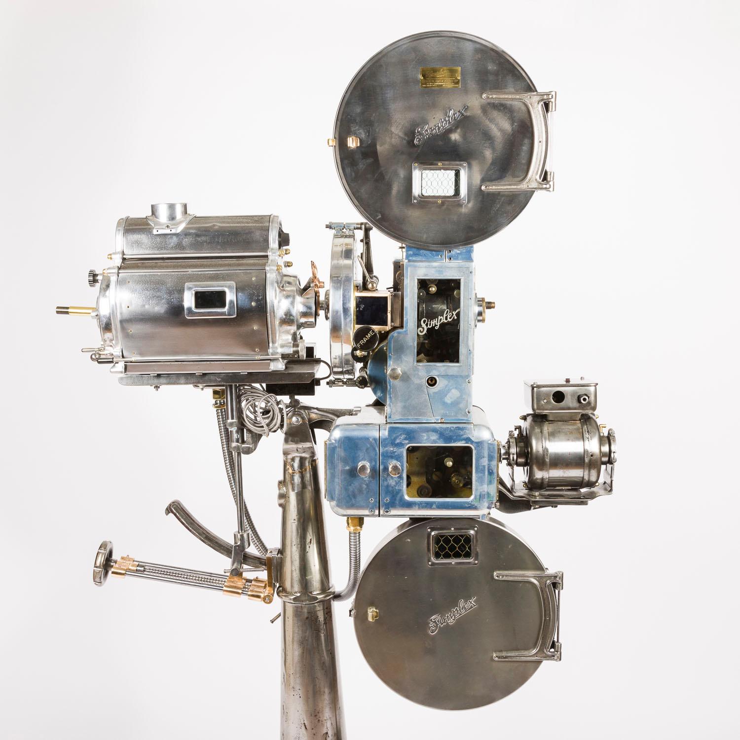 A 35 mm Simplex cinema projector by International Projector Corp of New York. Circa 1935.

Fitted with a Strong portable reflector arc lamp light box by The Strong Electric Corp of Toledo, Ohio. Now fitted with an E27 electric light.

With a