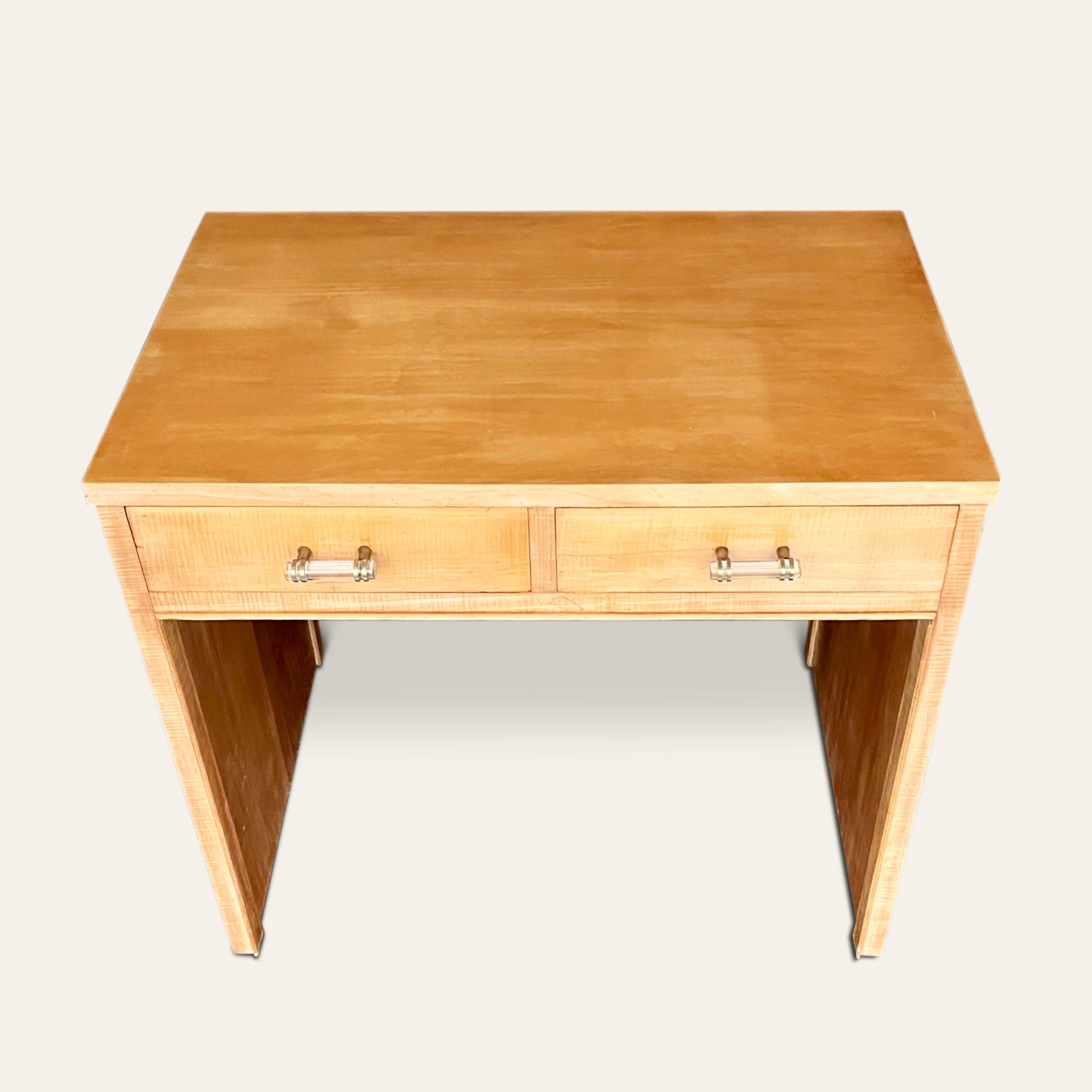 A 1930’s desk in the style of Jacques Adnet with two drawers to the front and  glass handles set in brass hardware.
