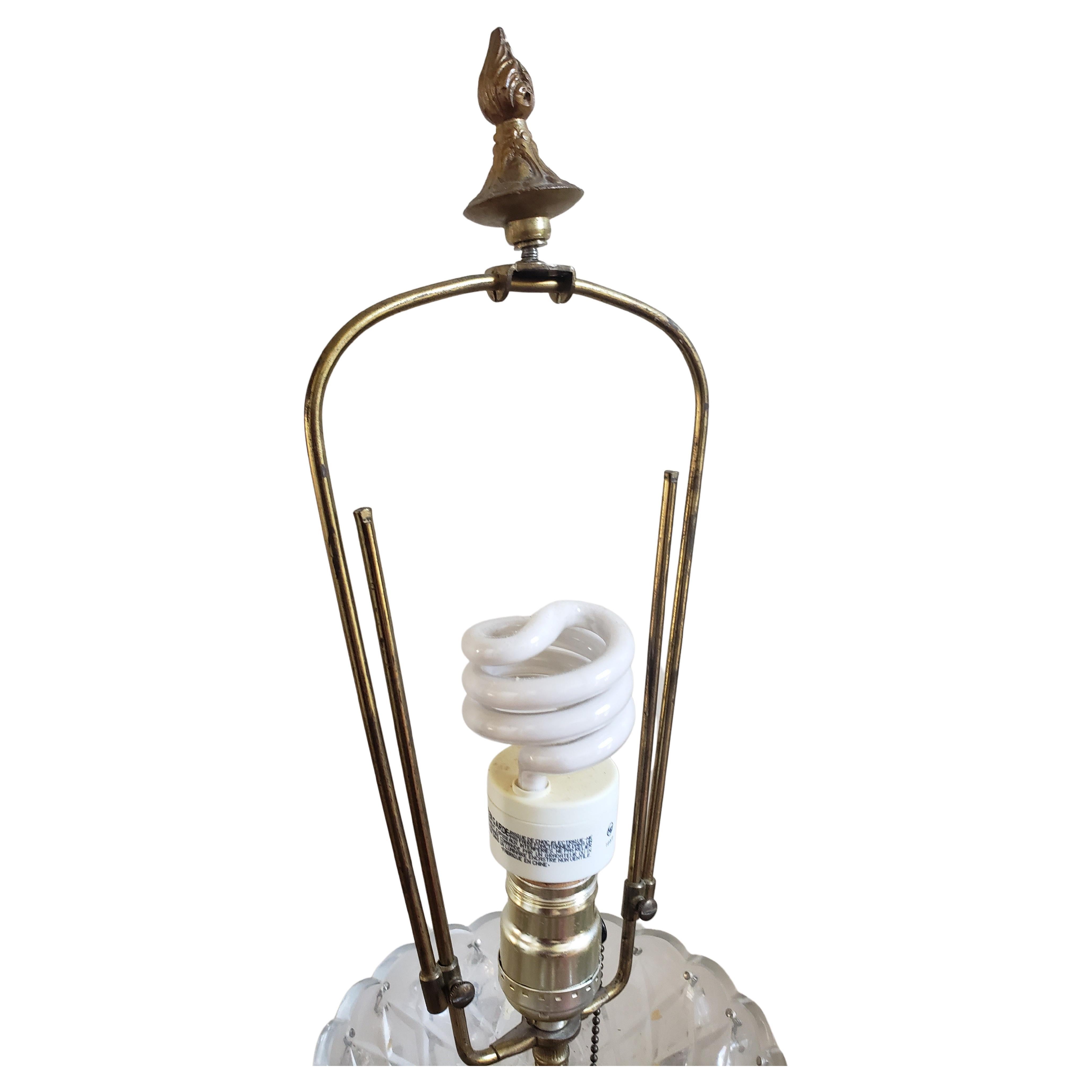 This beautiful early 20th century  table lamp gives off a lovely sparkle. It features a solid brass base with paw feet, a glass cut column topped with solid brass body, and surrounded with hanging lead crystal prisms and spear/arrow pendulums. Comes
