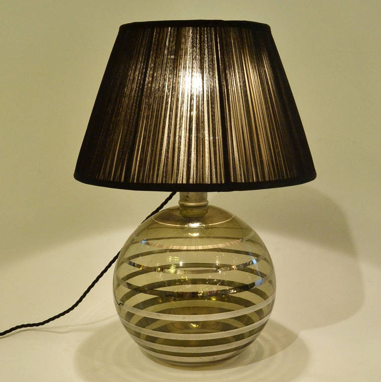 Art Deco Dutch smoked glass hand blown table lamp base with platinum cascading rings surrounding the globe.
The shade is handmade in sheer black silk with white lining.
