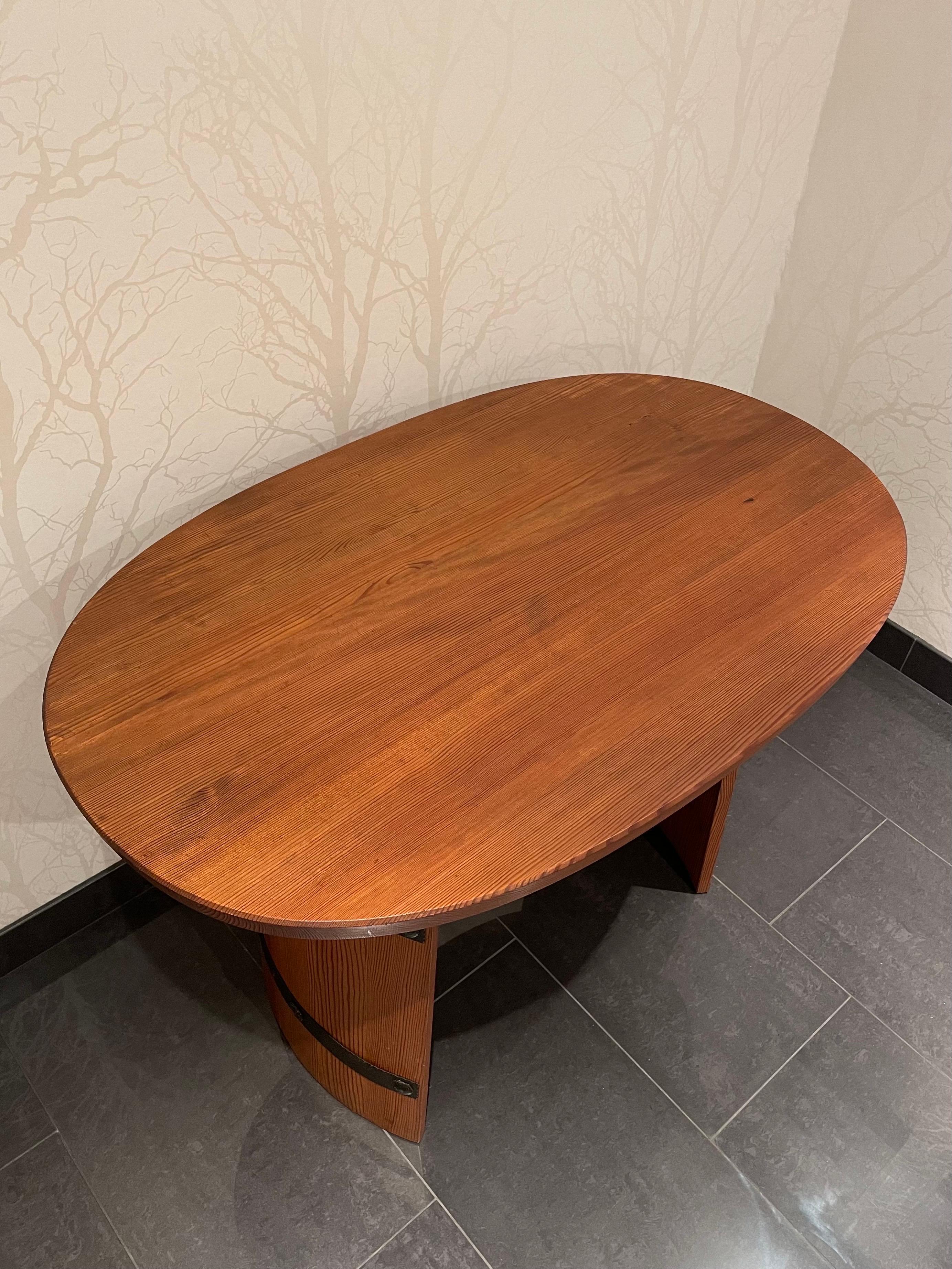 This is the Swedish solid stained pine coffee table manufactured by Åby Möbelfabrik in the 1930/40s

It comes with a 3.5 centimeter thick, oval shaped table top with an underlying shelf. 
The two curved barrel shaped legs are stabilized with two