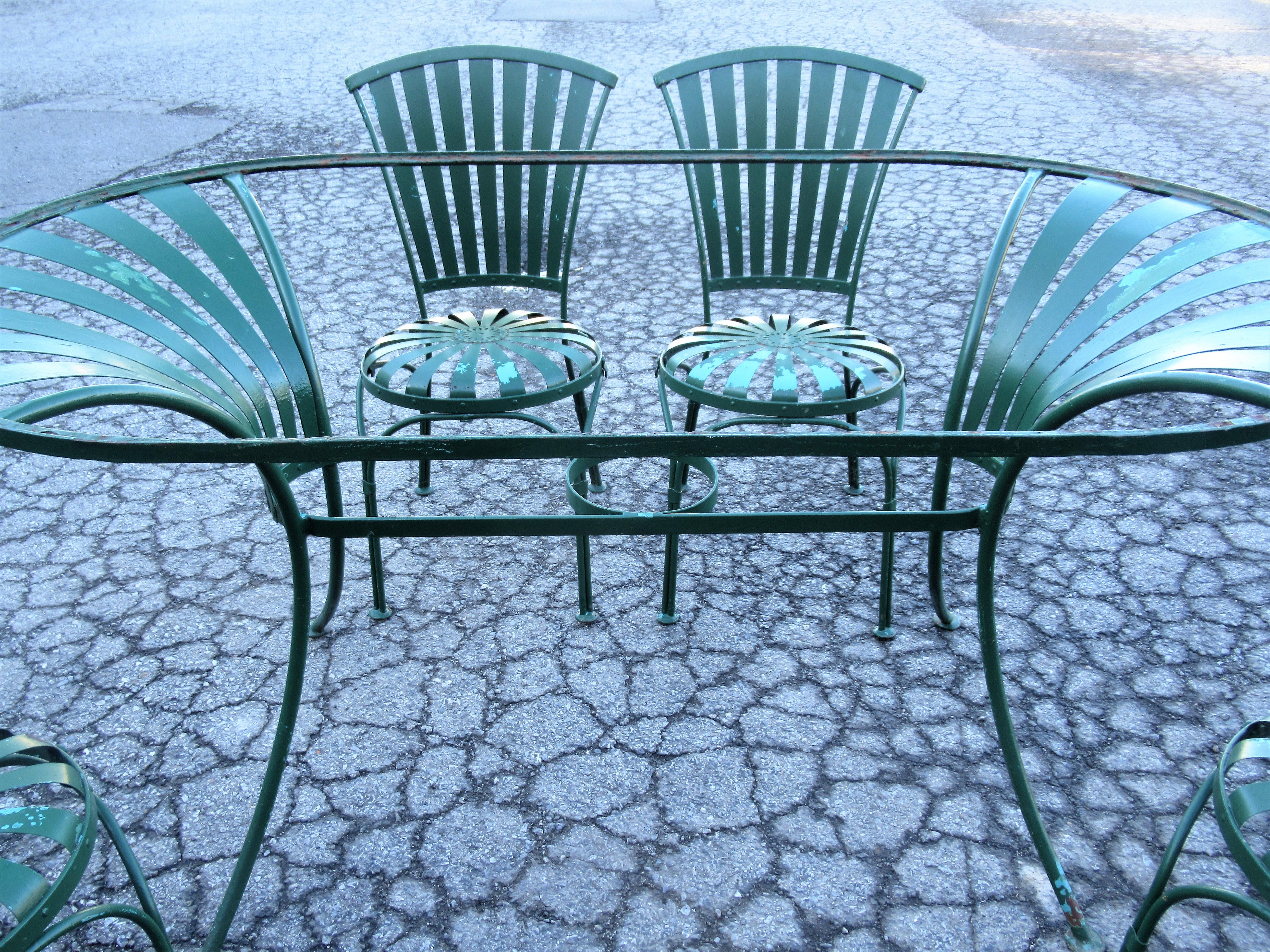 Francois Carre steel oval garden dining table and four matching riveted spring steel seat chairs in overall very good vintage condition, circa 1930. Table measures 60 inches wide x 33 3/4 inches deep x 29 inches high. Chairs measure 32 inches high x