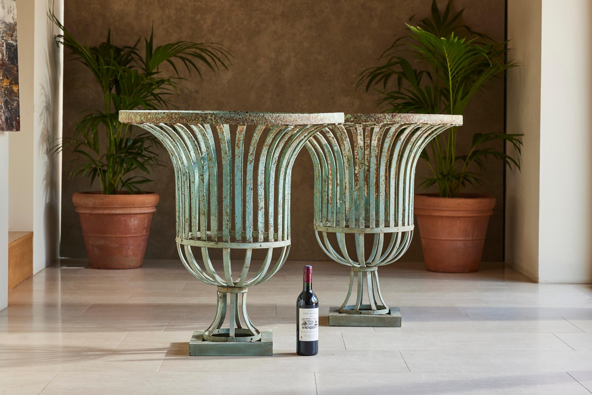 Over the years, this substantial pair of strapwork urns have developed a lovely turquoise patina. These work best when lined with moss and filled with plants. Alternatively, they are architectural pieces in their own right and could be a very
