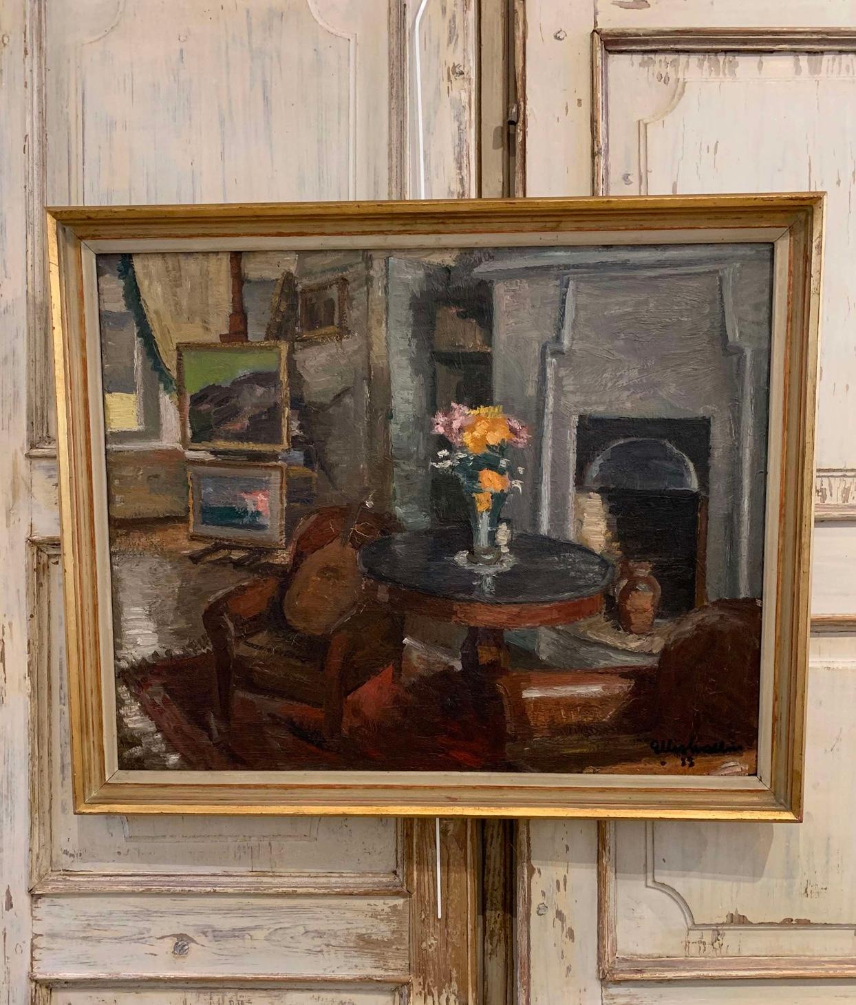 Questo olio su tela incorniciato raffigura un confortevole salotto pieno di mobili antichi e opere d'arte. 
In primo piano c'è un grande camino tradizionale con una coppia di comode sedie scandinave in pelle, uno strumento a corde appoggiato con