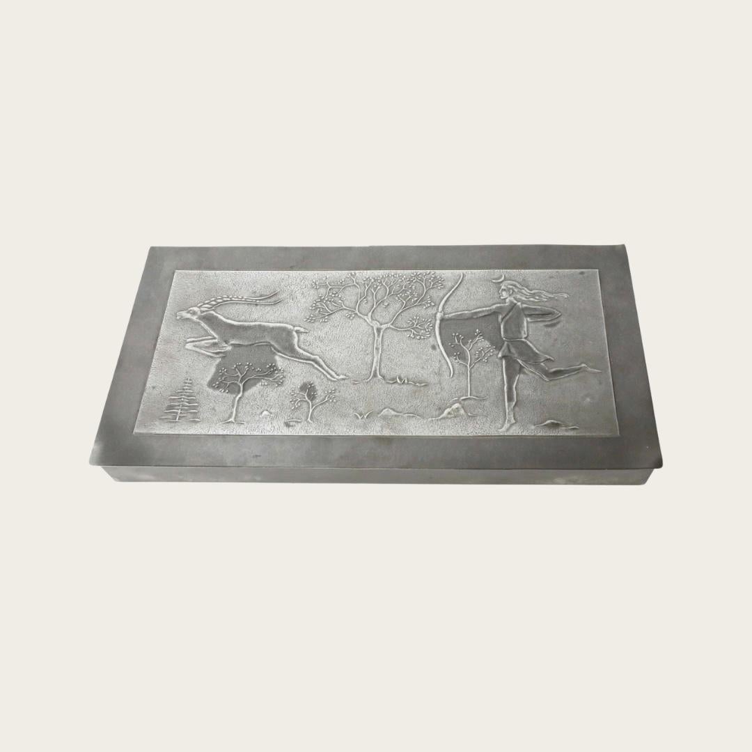 1930s, Sweden. Pewter box with an Art Deco forest relief of an archer and deer. Wood-lined interior and the manufacturers mark on its underside.