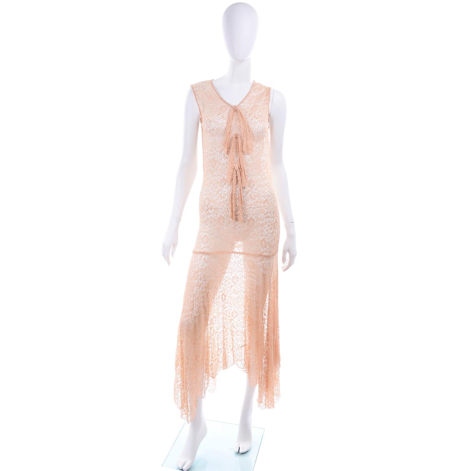 This is a 1930's vintage stretch lace dress in a peach / tan color with a matching open front jacket. The dress has 3 bows down the front of the drop waist bodice and a bias asymmetrical hemline skirt. The cardigan style jacket has long sleeves and