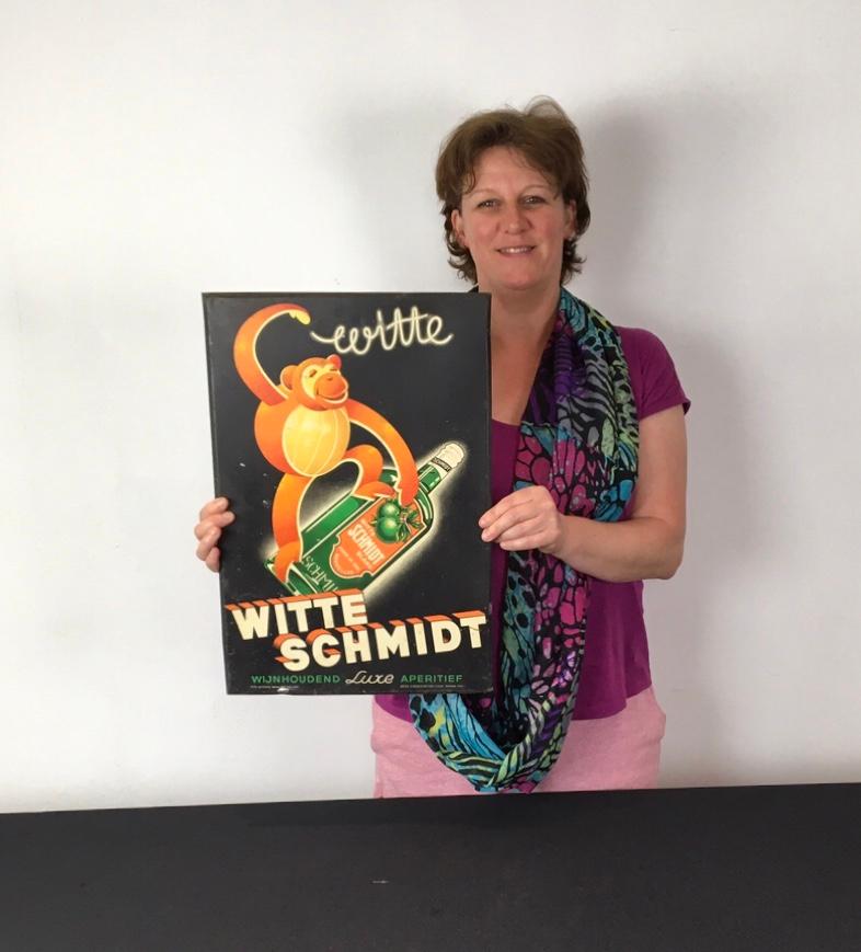 1930s Sign for Belgian Liquor Wiite Schmidt. 
An eyecatching advertising sign : black background with an orange monkey or ape who's holding a bottle of the liquor.
It's a tin sign - tin plate mounted on cardboard which dates from the Art Deco