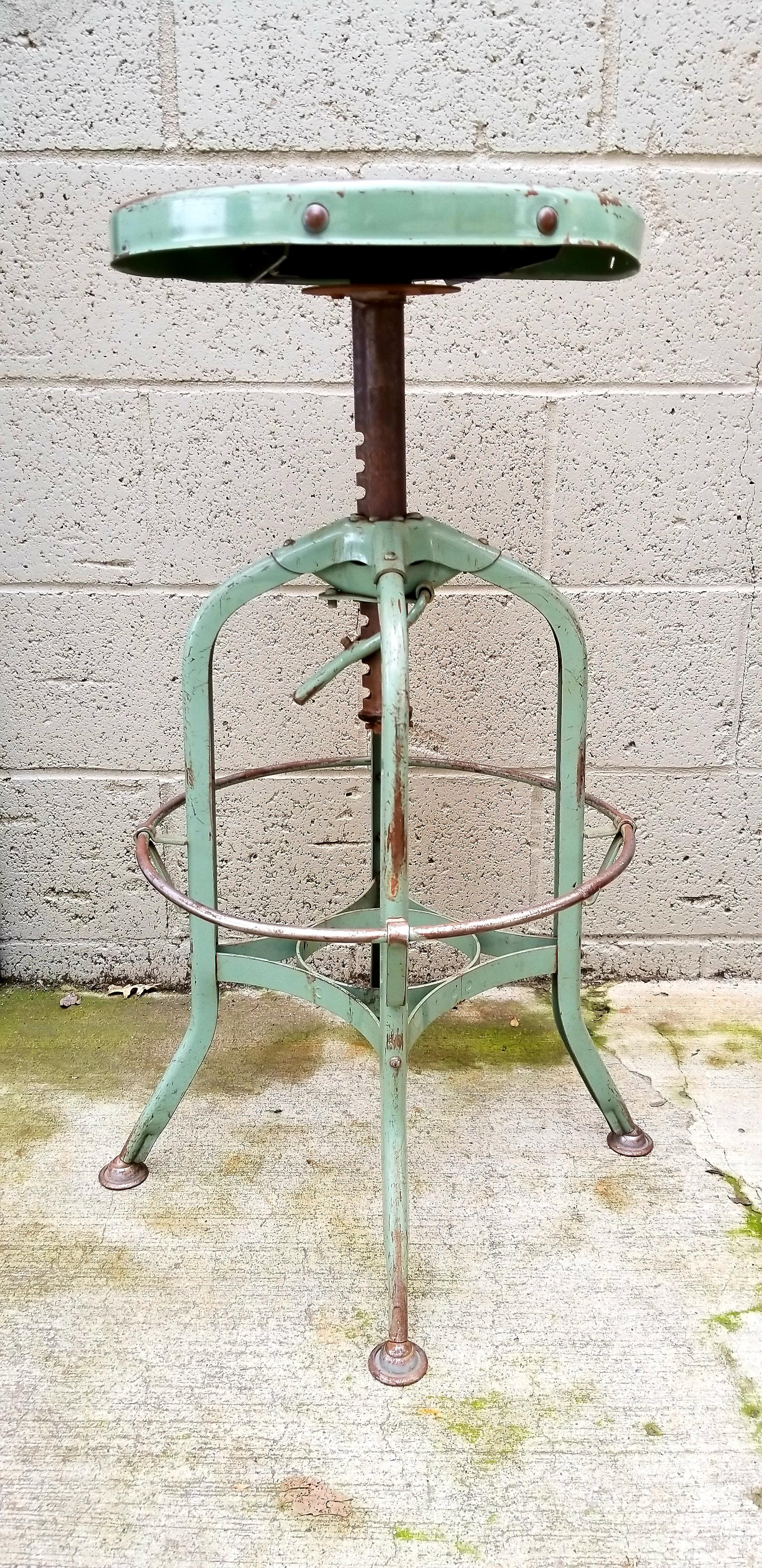 Original painted steel Toledo Industrial stool. A perfectly worn patina with dings and dents from years of use enhance this stool with charm and character. Measures: Seat diameter measures 14.25 inches, height is adjustable.