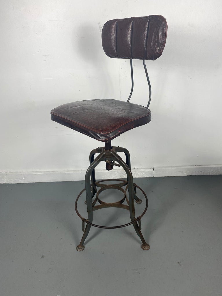 1930s industrial adjustable height swivel stool with back by Toledo Metal Furniture Company, Retains extremely rare oil cloth covers,

 enameled steel base and frame with adjustable height bentwood swivel seats. Adjustable bentwood backs.Minor