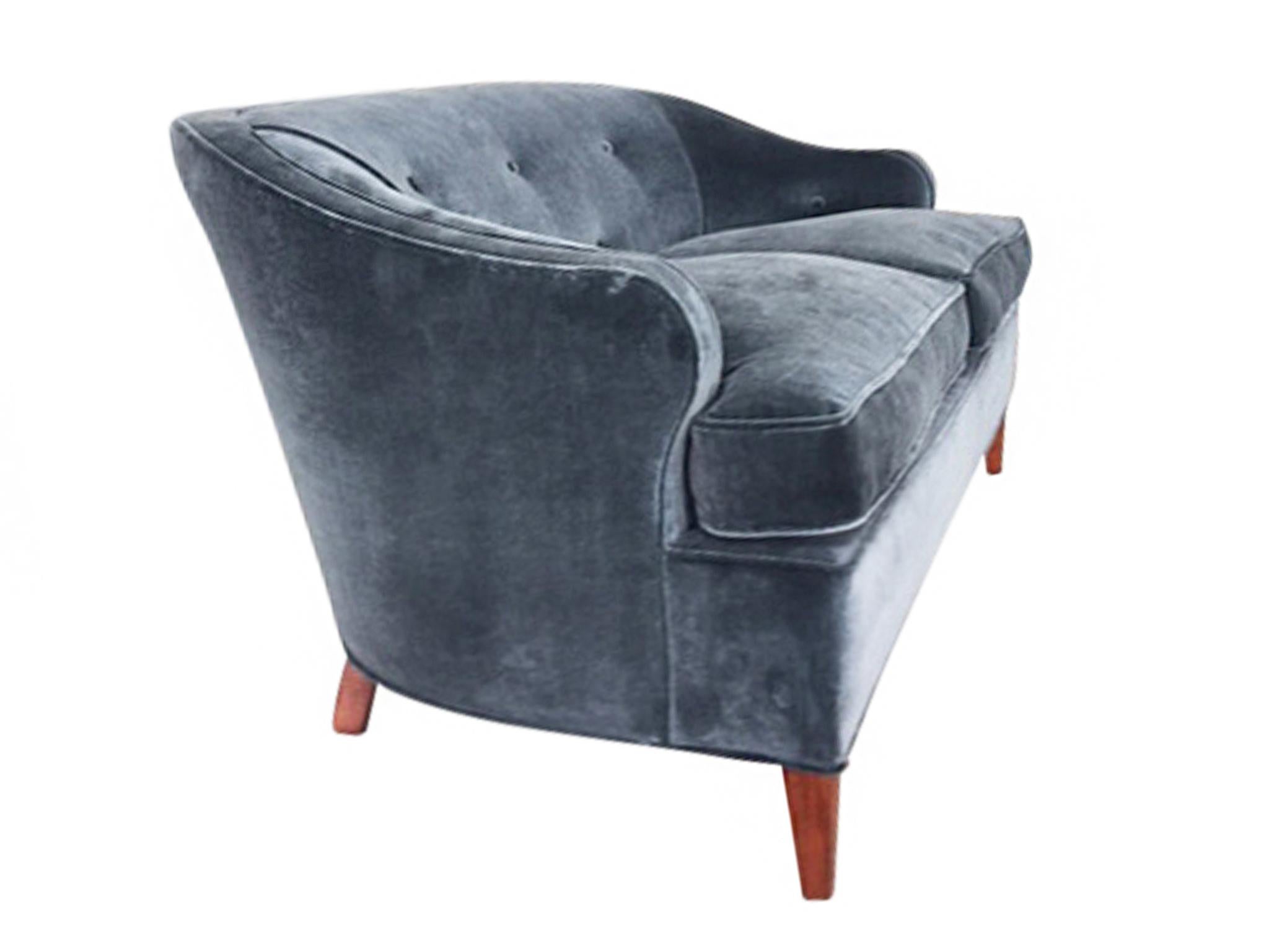 This 1930s Art Deco settee is newly reupholstered in a smoky blue brushed velvet. The fabric is soft and covers new down cushions, creating an ideal immersive surface for comfort and rest. With clean lines and rounded edges, the sofa strikes a