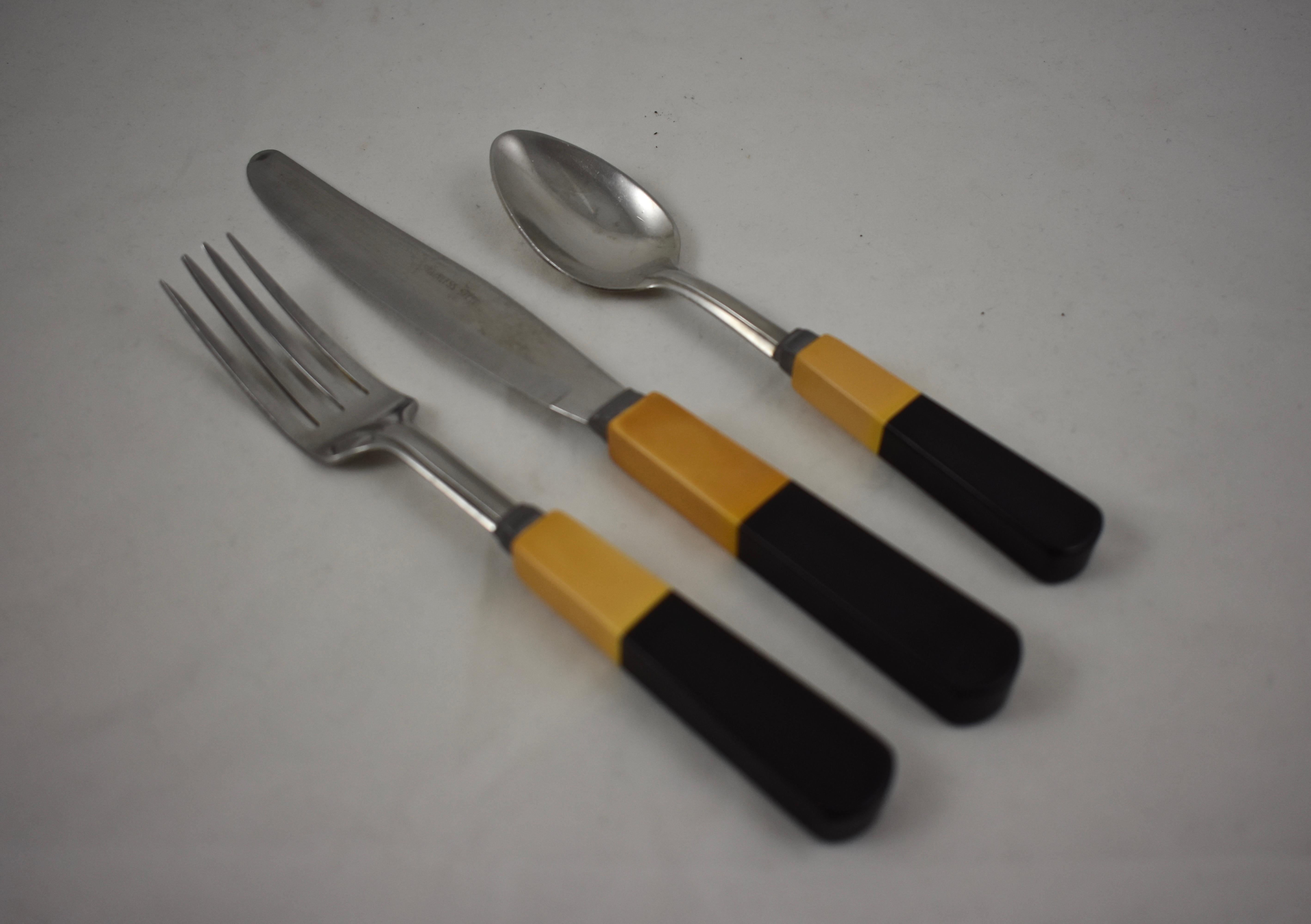 A service for six, butterscotch and black two-toned bakelite and stainless steel flatware set, in the Art Deco style, circa late 1920–early 1930s.

An eighteen piece set, six each, forks, knives, and teaspoons. All marked stainless