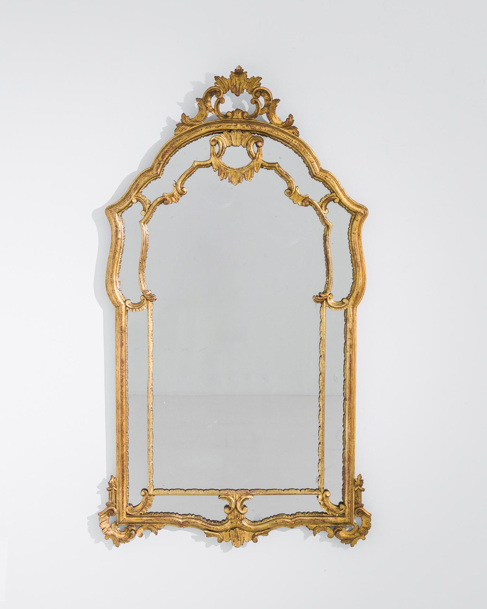 A giltwood framed mirror from Italy, produced circa 1930. A veritable concerto of long lines of golden wood frames, cuts across, and crowns a gorgeous piece of arched glass, framed by mirror glass panels in a typical Venetian style. A conscious riff