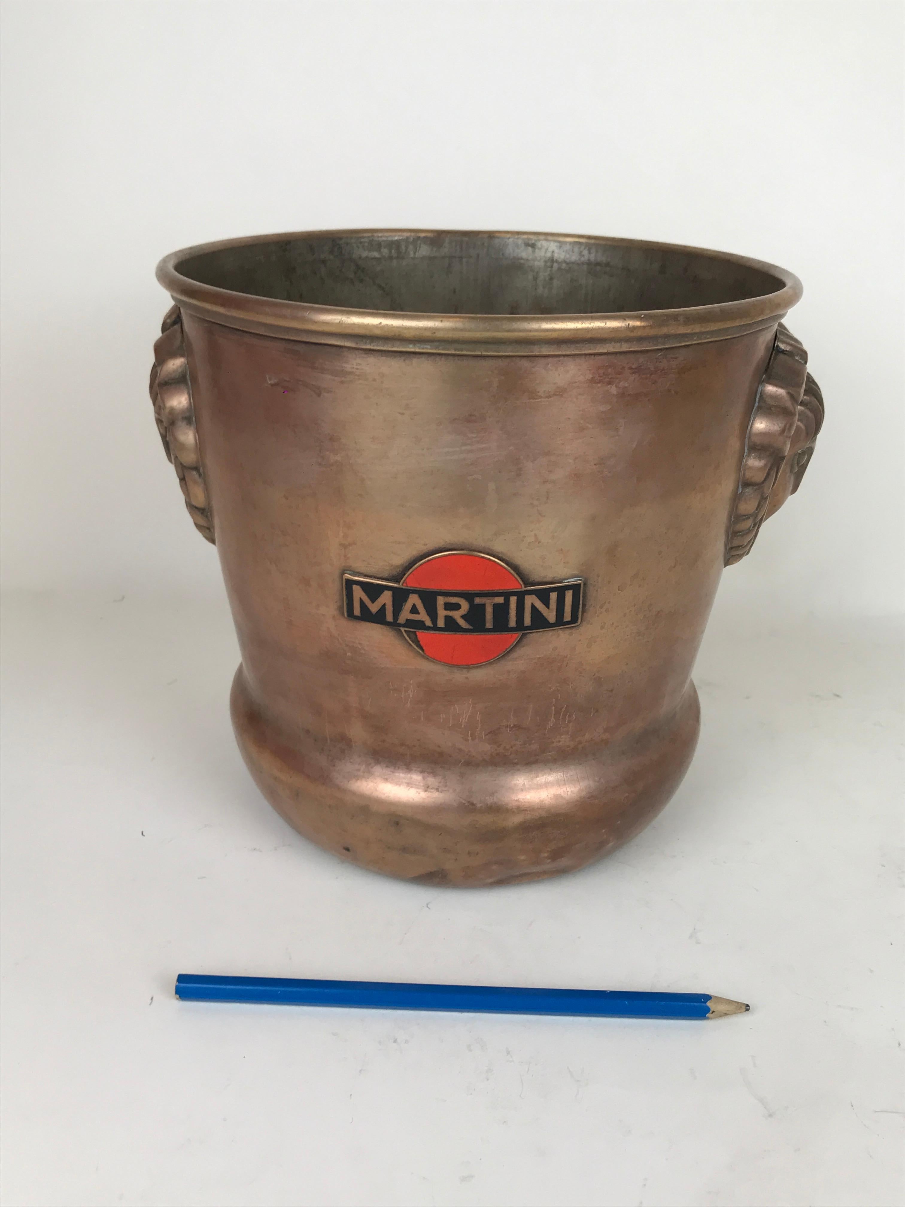 Splendid vintage Martini ice bucket by Martini in brass with side reliefs in the shape of Art Decò style faces of young girls, made by G. Strola in Turin Italy.
Both sides present metal enamel Martini logos.

Marked on bottom G. Strola