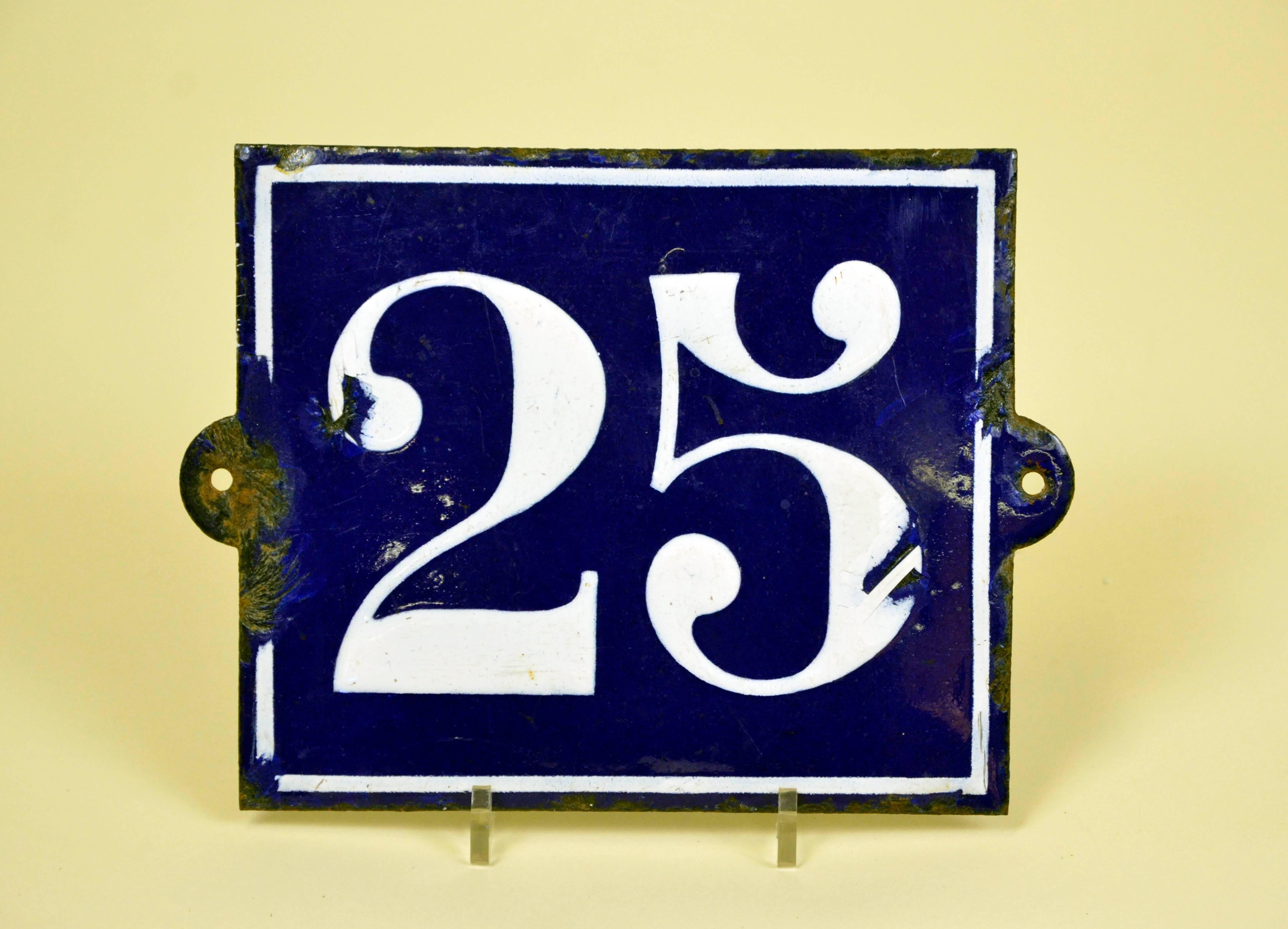 Vintage enamel metal street sign N 25 in white on dark blue background and white profile. The sign is slightly curved and can be fixed to a wall with two screws, left and right.
 