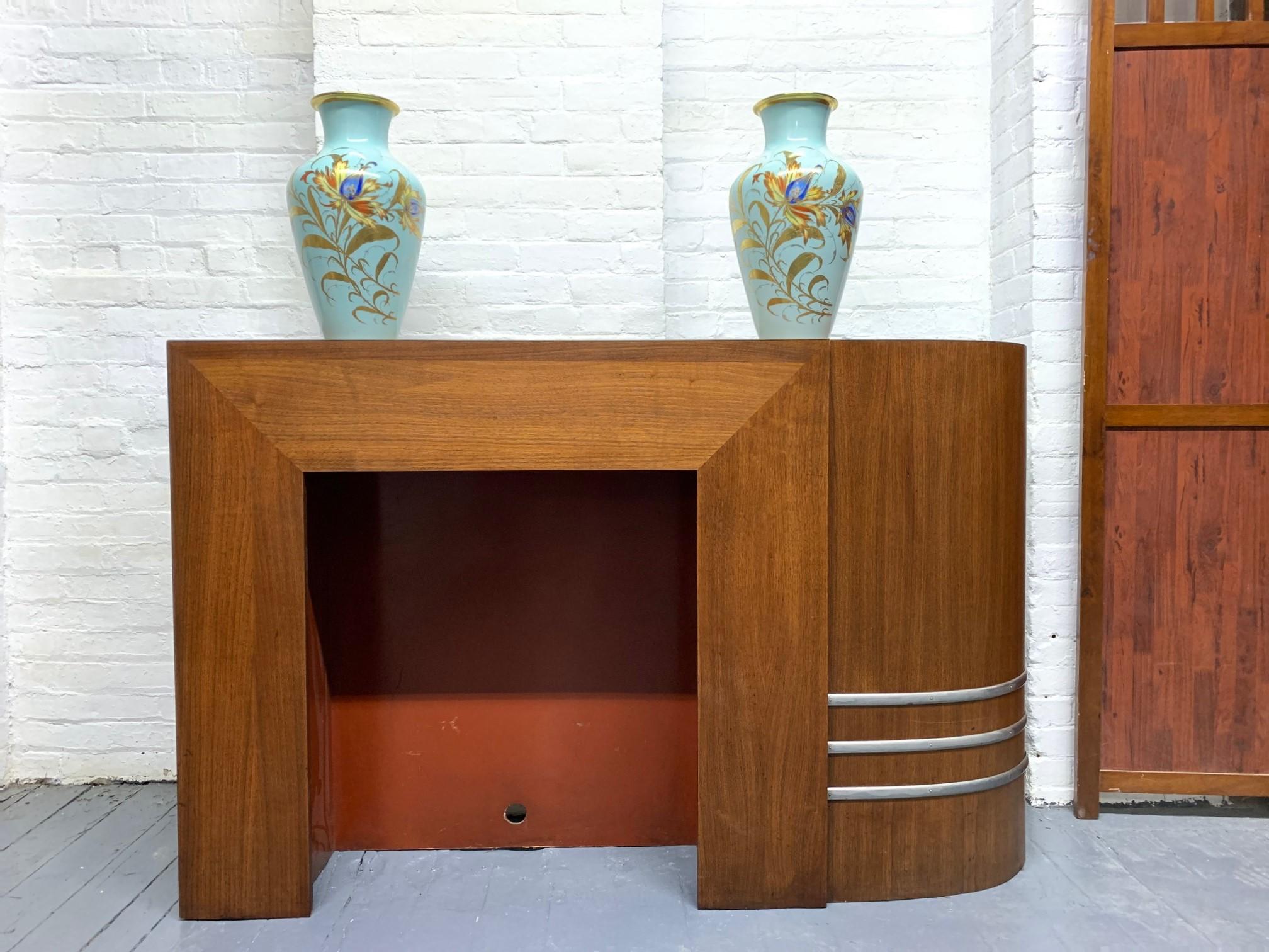 1930s walnut Art Deco mantel. Well made. The mantel has one curved side with metal detail toward the bottom.
Vases not included. 

 